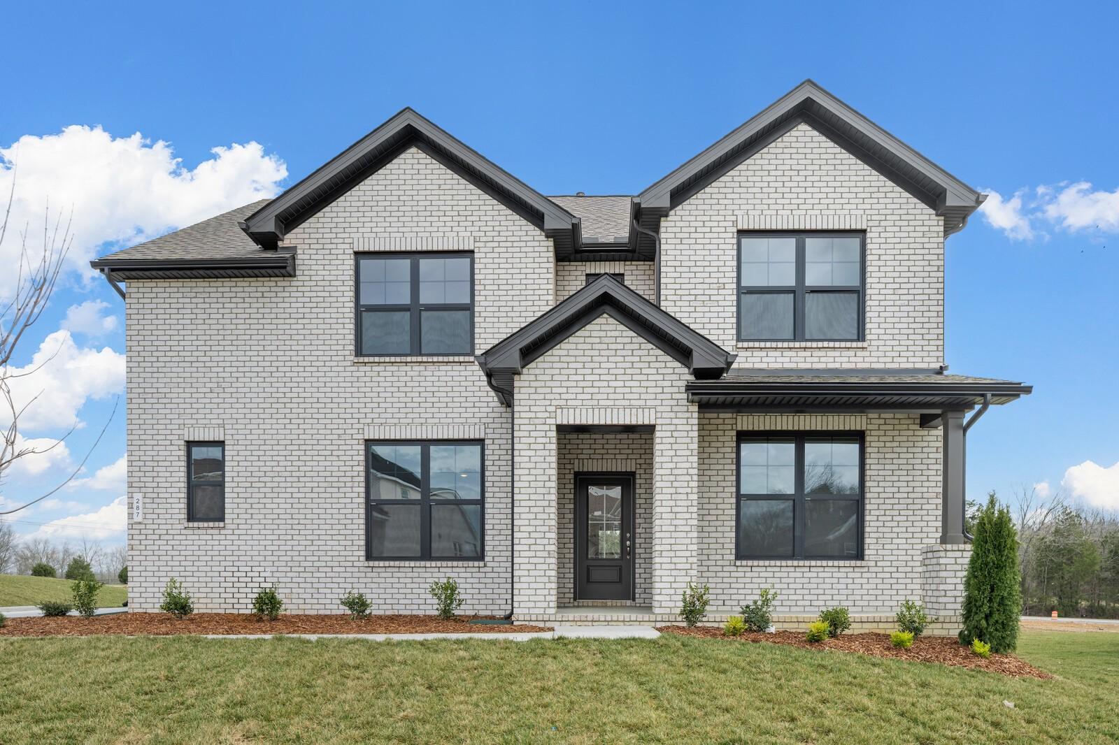 Modern two-story white brick home with black trim, large windows, covered porch, and landscaped yard in Benders Cove, Mt. Juliet