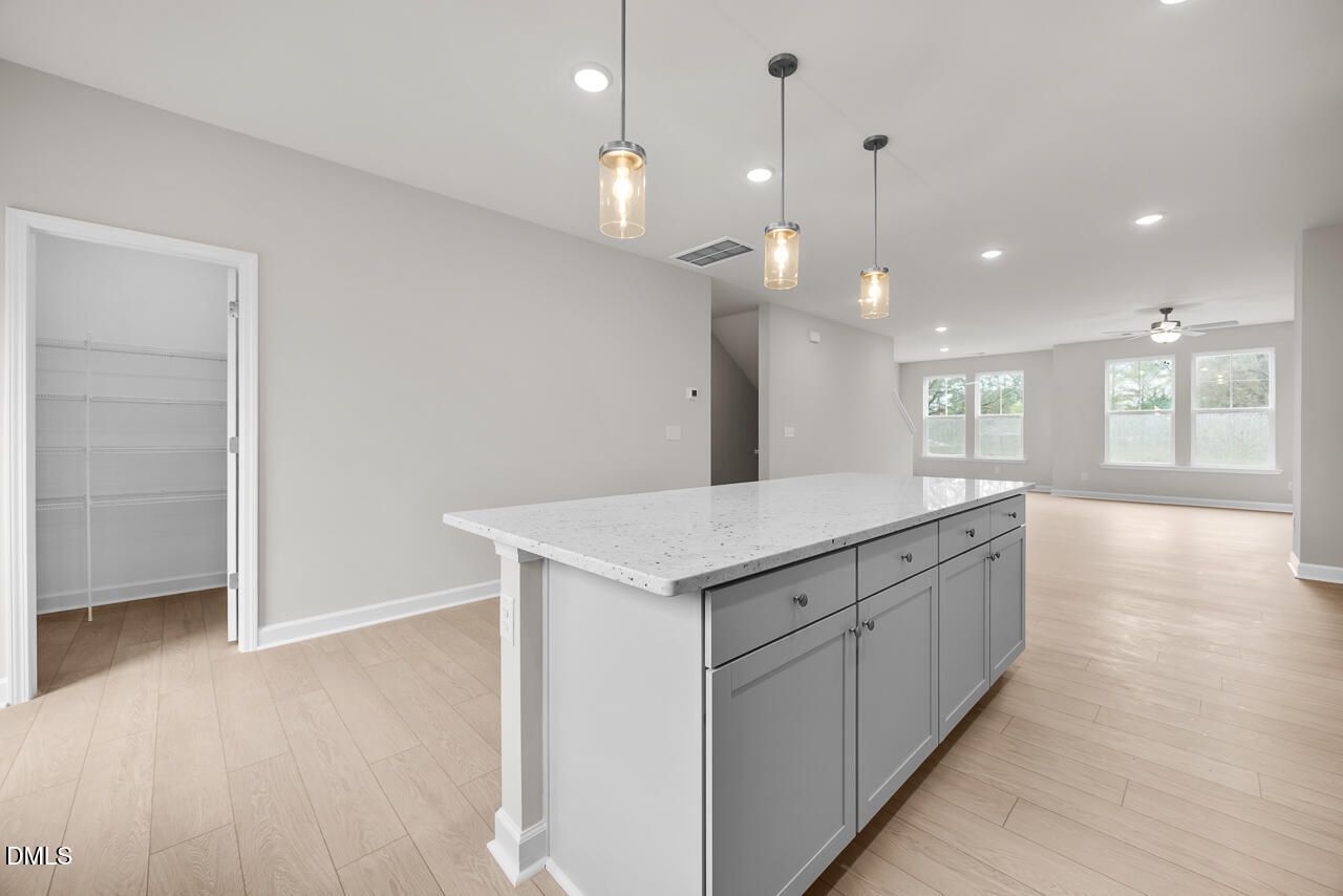 Modern kitchen with white quartz island, gray cabinets, pendant lights, open layout in The Avery floor plan, Knightdale NC