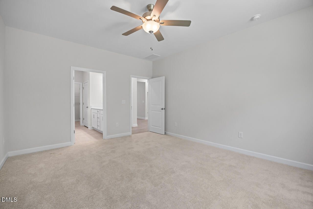 Spacious carpeted primary bedroom with ceiling fan and en-suite bath access in Davidson Homes Daphne D, Zebulon NC