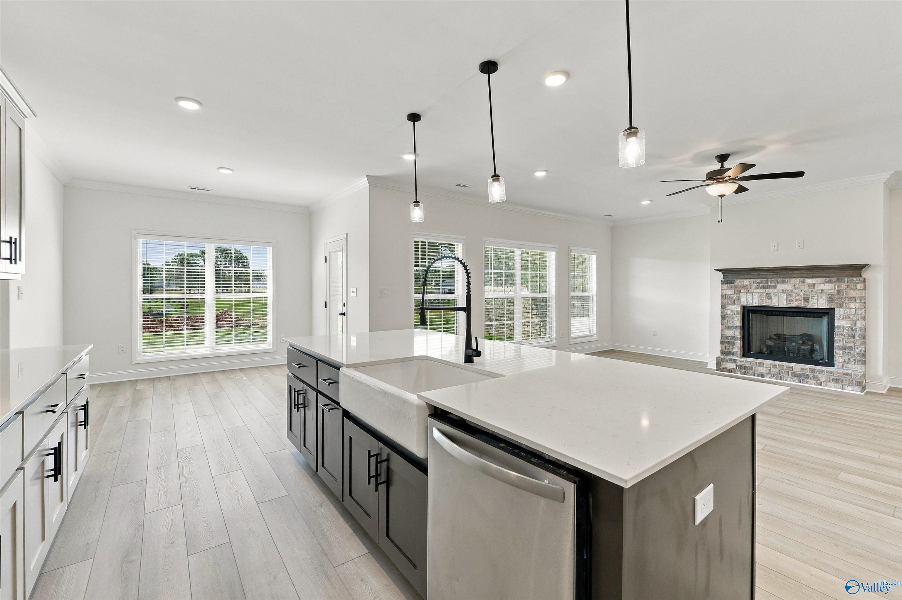 Open-concept kitchen with farmhouse sink, large island, and brick fireplace in Davidson Homes The Valencia, Huntsville, Alabama