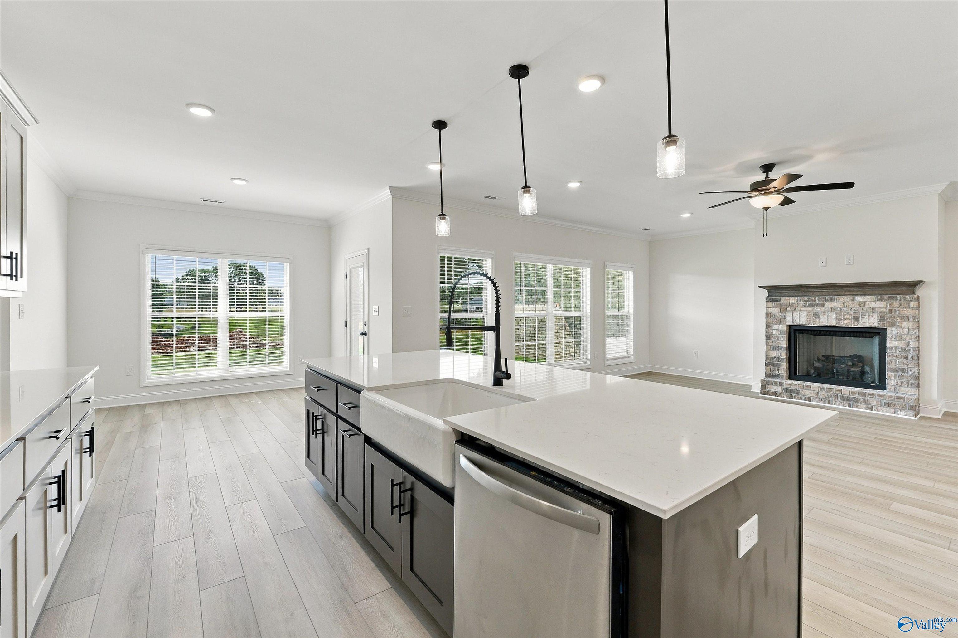 Open-concept kitchen with farmhouse sink, large island, and brick fireplace in Davidson Homes The Valencia, Huntsville, Alabama