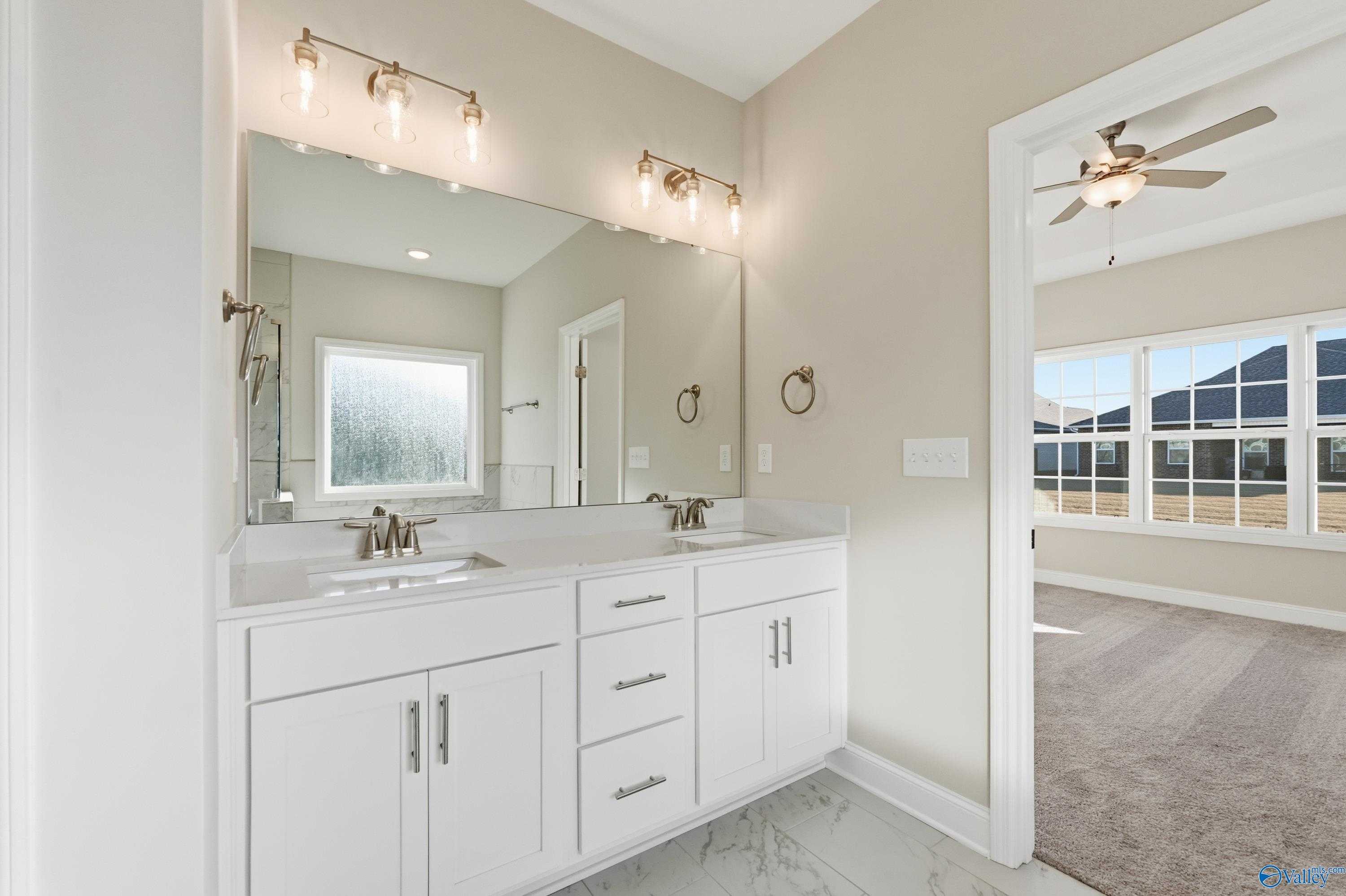 Modern master bathroom featuring double white vanity, large mirror, and frosted window in Davidson Homes The Montgomery B, Toney, Alabama