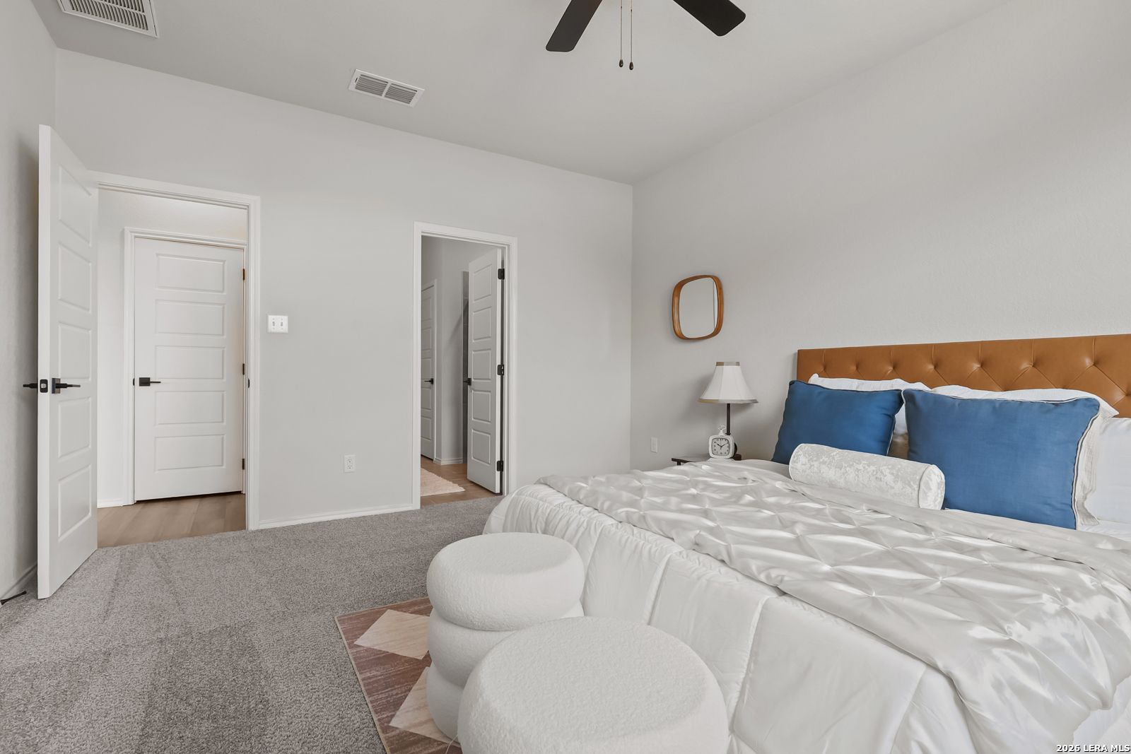 Elegant master bedroom with king bed, orange headboard, blue pillows, and open en-suite door in Davidson Homes The Daphne H, Seguin, Texas