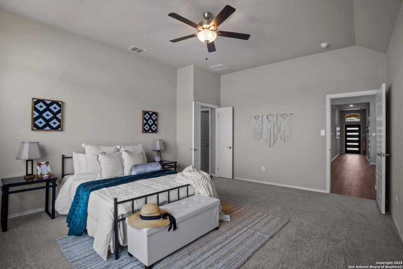 Serene master bedroom with king bed, blue bedding, ceiling fan, and walk-in closet in Davidson Homes The Collin B, Seguin, Texas