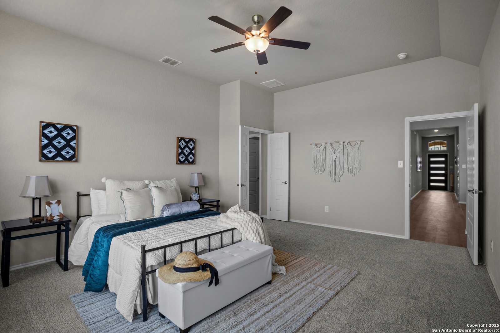 Serene master bedroom with king bed, blue bedding, ceiling fan, and walk-in closet in Davidson Homes The Collin B, Seguin, Texas