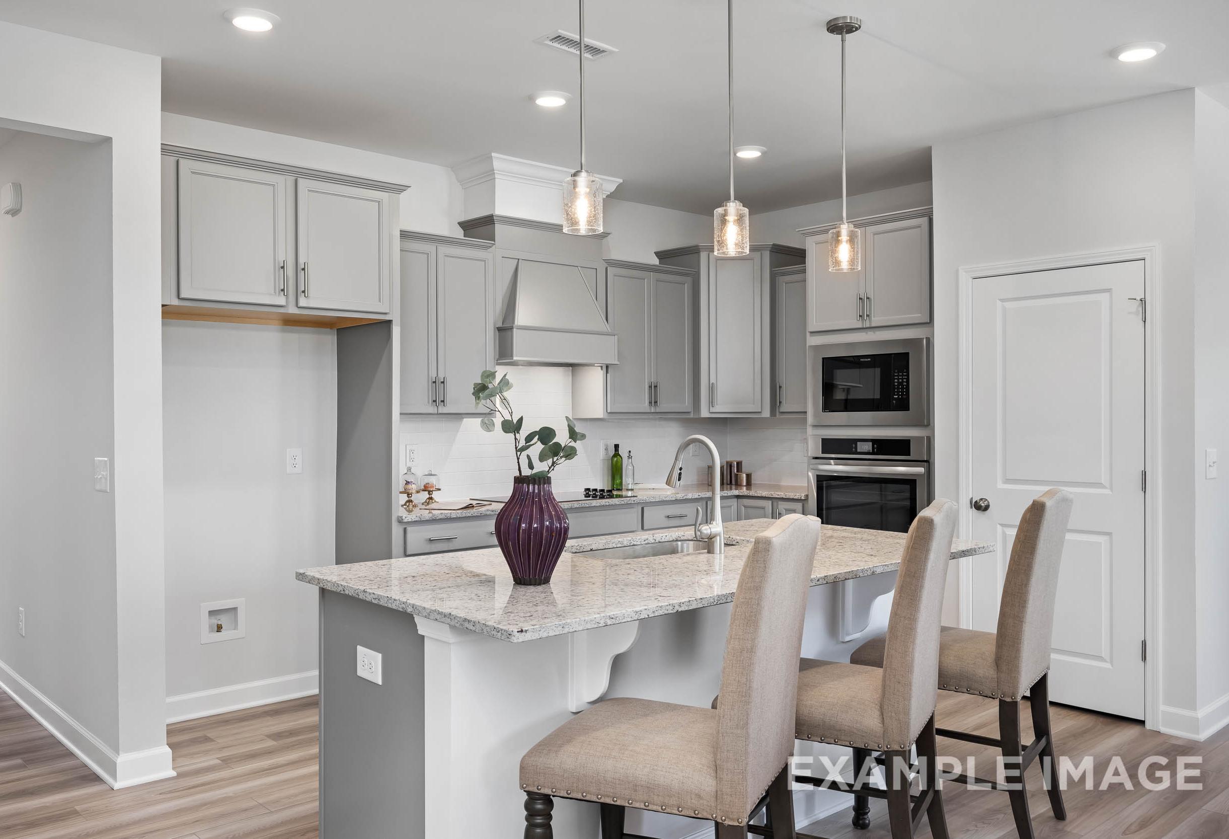 Modern kitchen in The Daphne C Davidson Homes design, Lillington NC, with white shaker cabinets, quartz island, pendant lights
