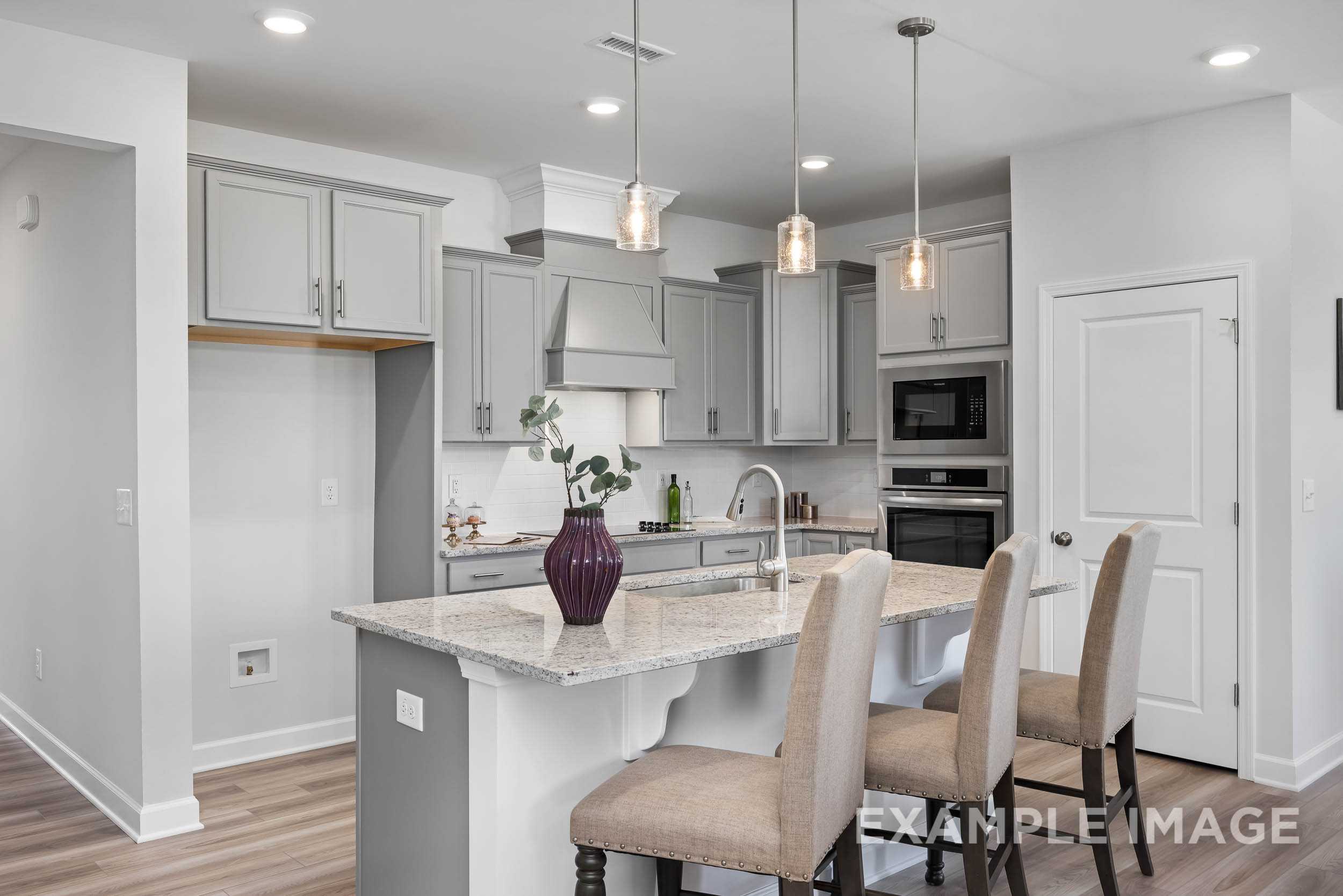 Modern kitchen in The Daphne C Davidson Homes design, Lillington NC, with white shaker cabinets, quartz island, pendant lights