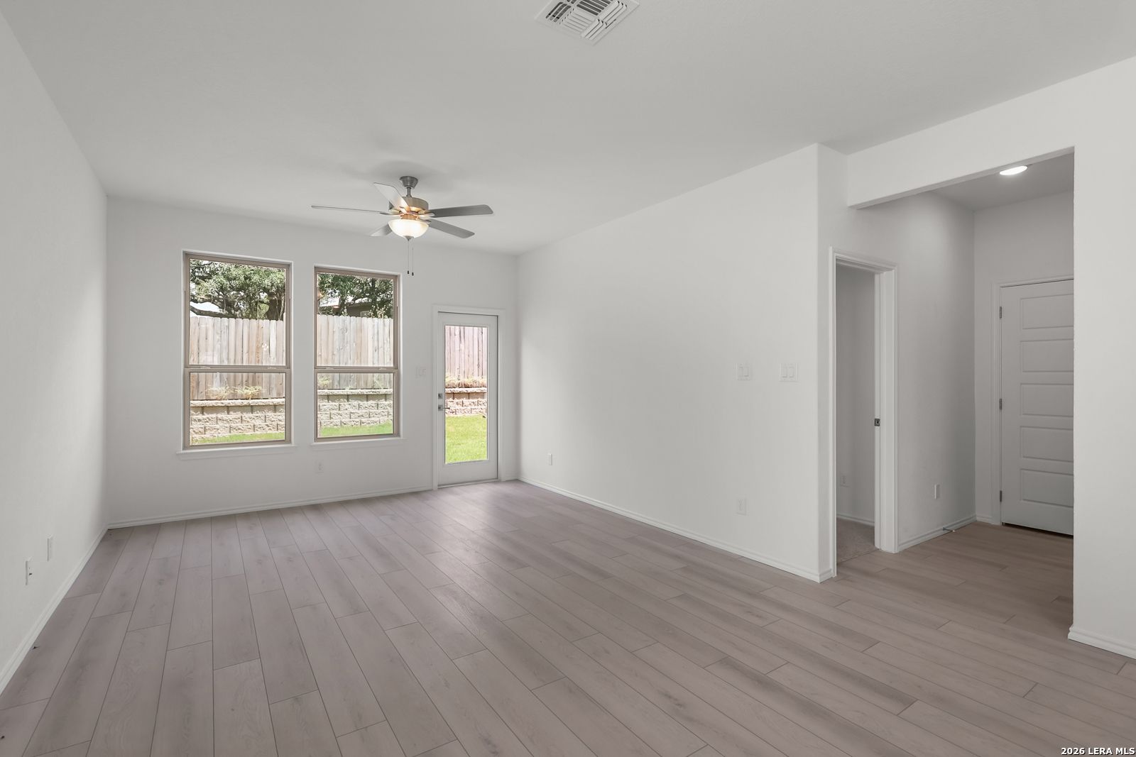 Bright, open-concept living area with wood-style flooring in The Gillian C plan at Meadows at Oak Creek, San Antonio.