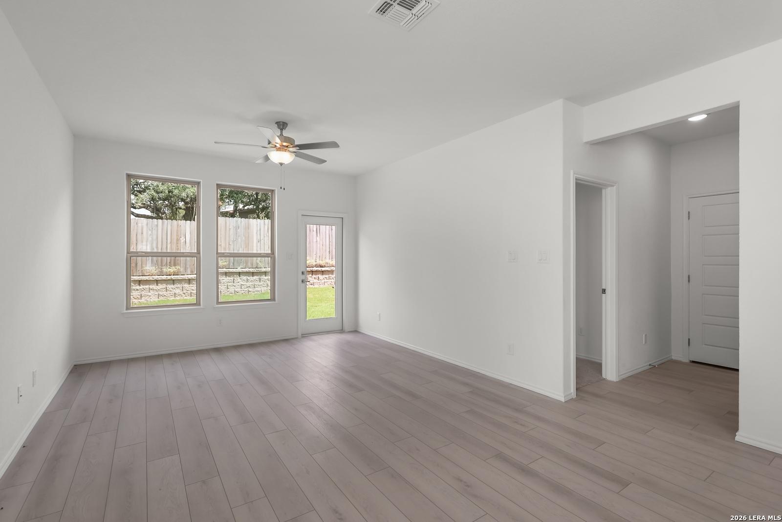 Bright, open-concept living area with wood-style flooring in The Gillian C plan at Meadows at Oak Creek, San Antonio.