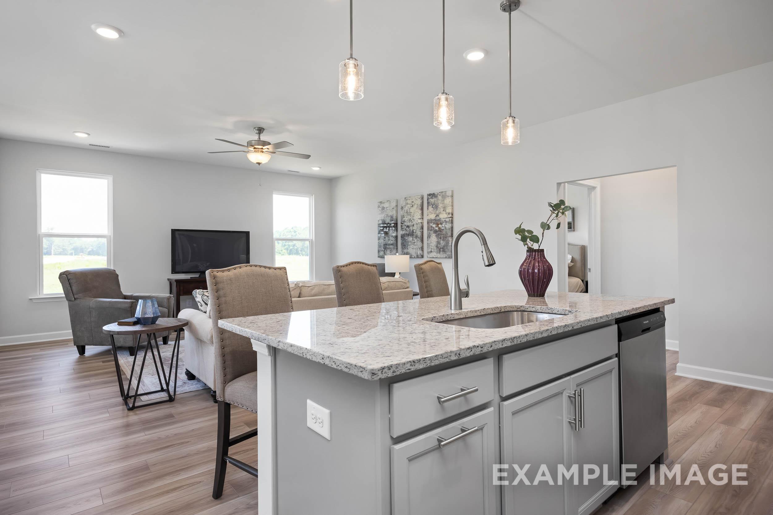 Spacious open-concept kitchen and living room in The Daphne C, featuring granite island, pendant lights, and cozy seating by Davidson Homes