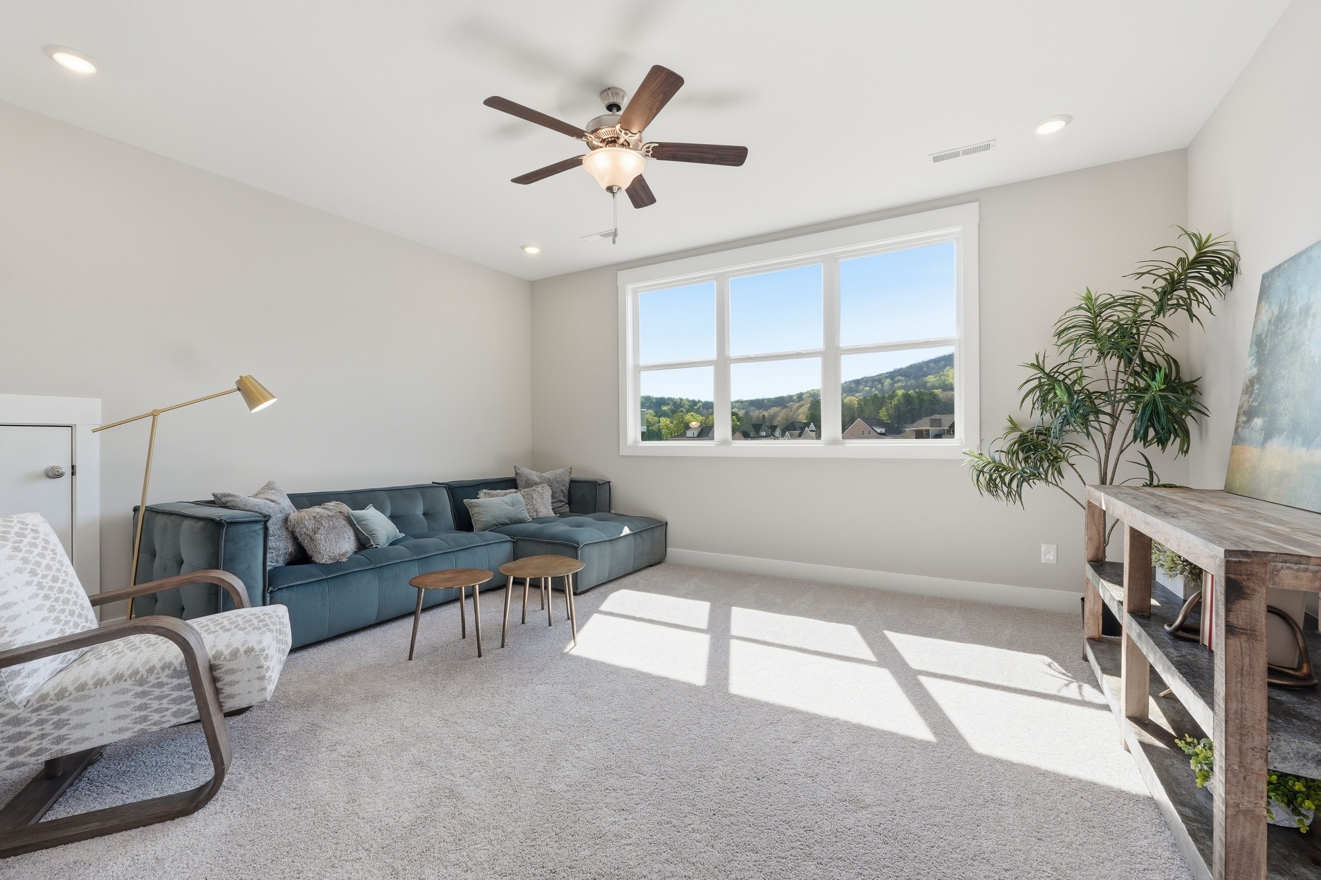Cozy loft seating area at The Meadows at Hampton Cove in Owens Cross Roads Alabama with blue velvet sofa, armchair, and mountain view windows