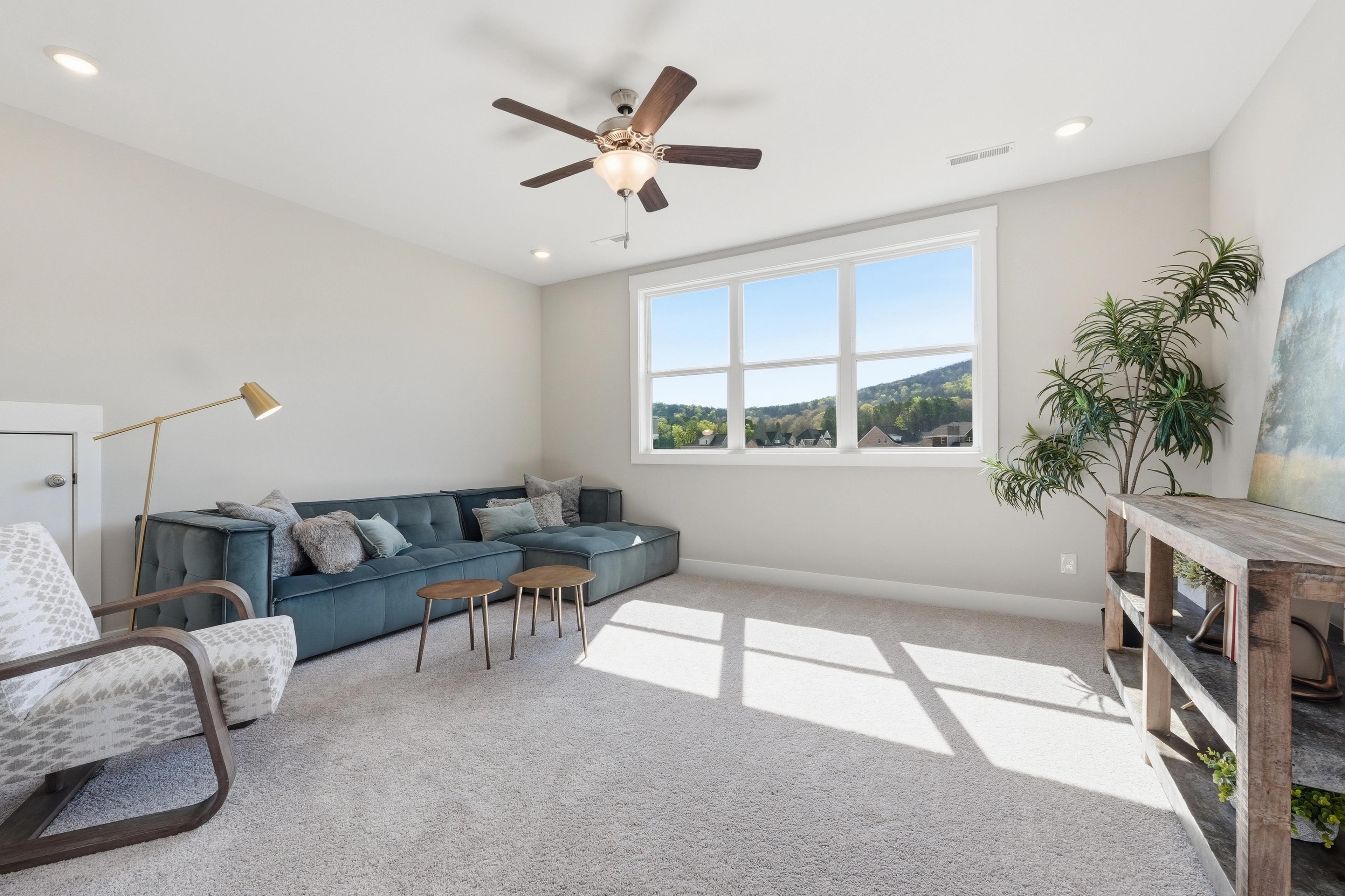 Cozy loft seating area at The Meadows at Hampton Cove in Owens Cross Roads Alabama with blue velvet sofa, armchair, and mountain view windows