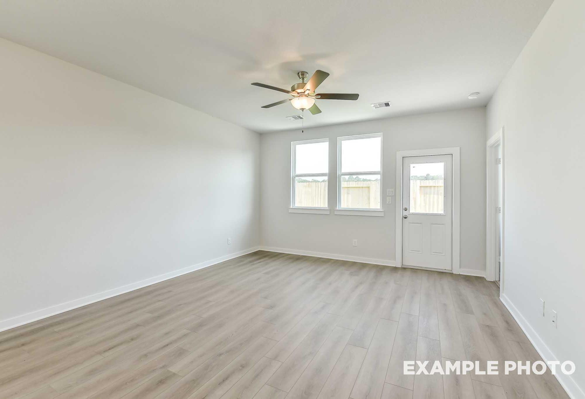 Bright open-concept living room in The Colorado by Davidson Homes with luxury vinyl plank flooring, ceiling fan, and rear exit door.