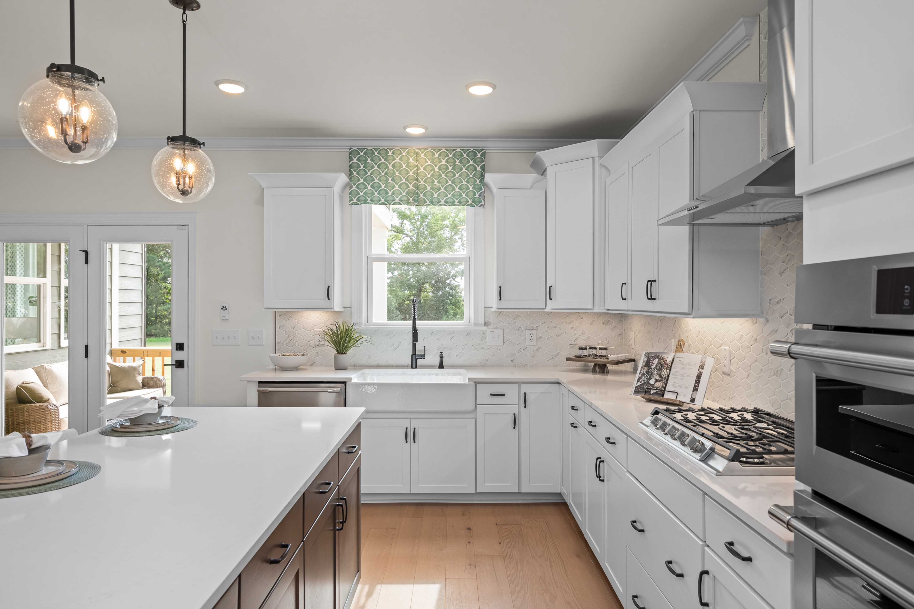 Modern kitchen in Laneridge Estates Raleigh NC with white shaker cabinets, farmhouse sink, quartz island, and stainless appliances