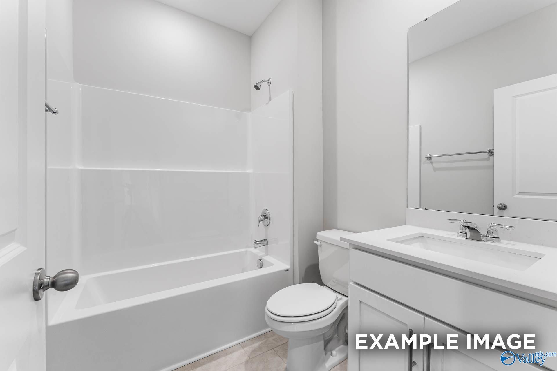 Bright white bathroom with tub-shower combo, vanity sink, mirror in Evermore Homes The Madison D, Madison, Alabama
