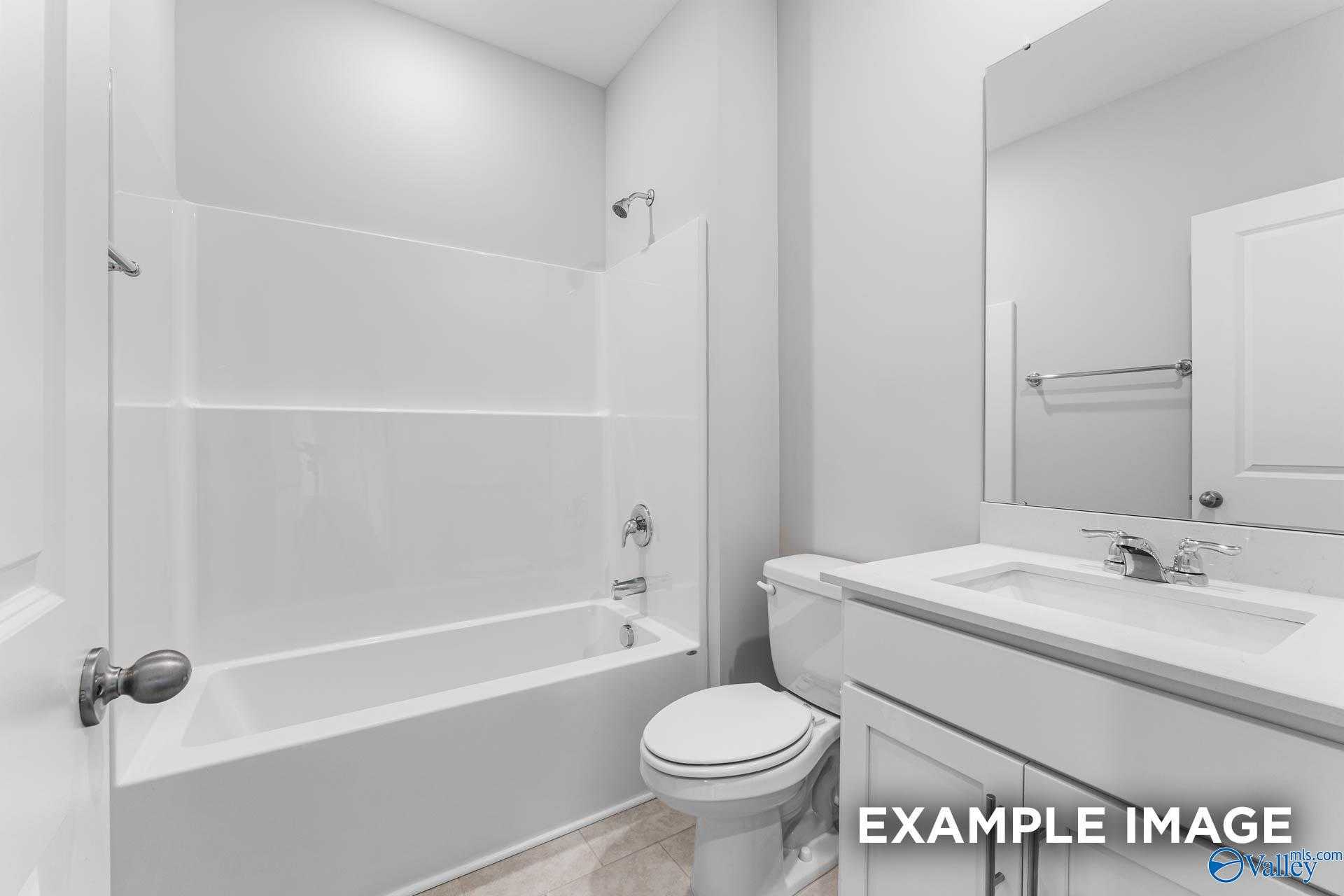 Bright modern bathroom with white tiled tub, glass shower, vanity, and mirror in Davidson Homes The Madison A, Harvest, Alabama