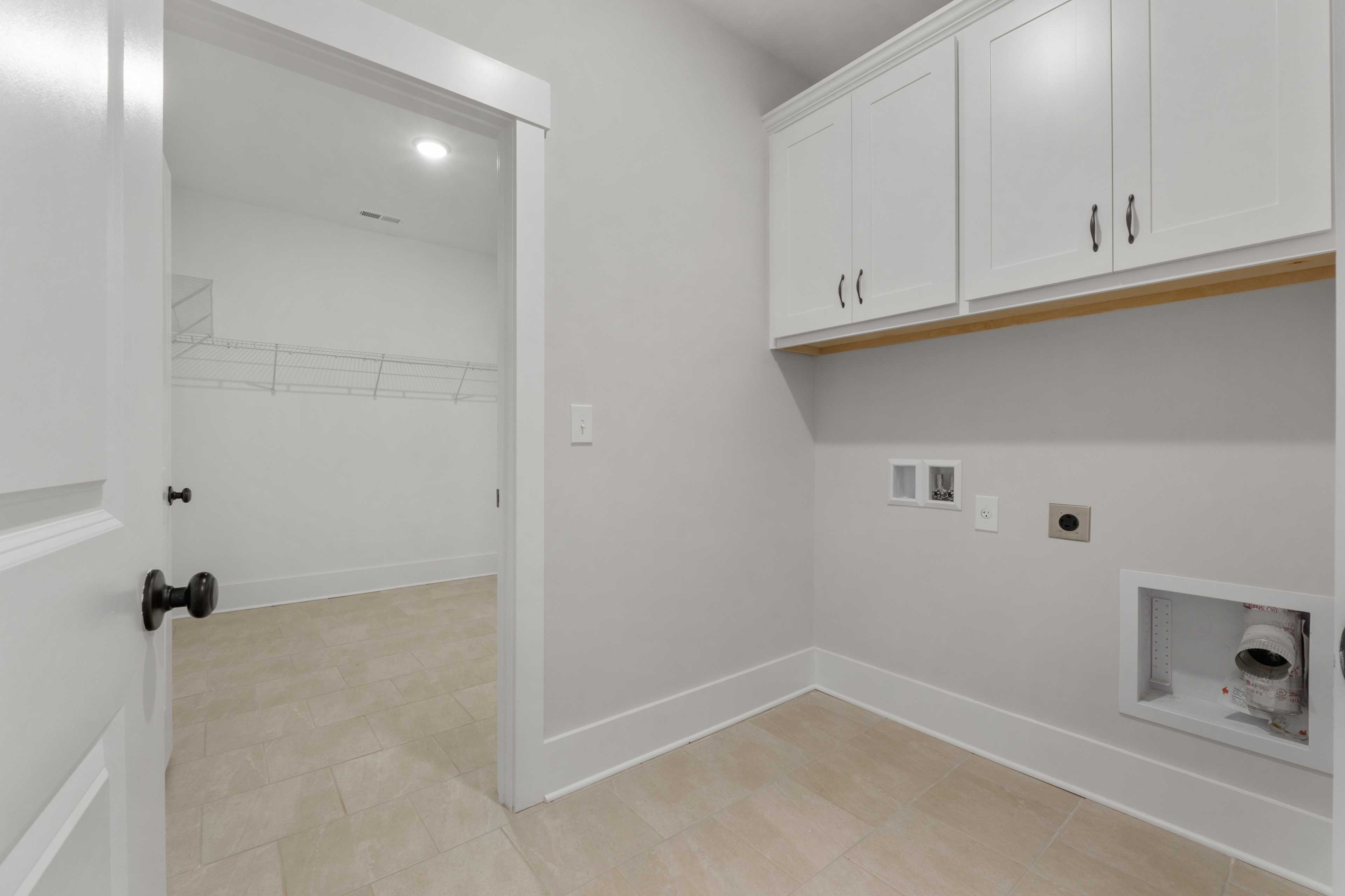 Spacious laundry room at The Villas at Barnett's Crossing in Madison Alabama with white cabinets and washer dryer hookups