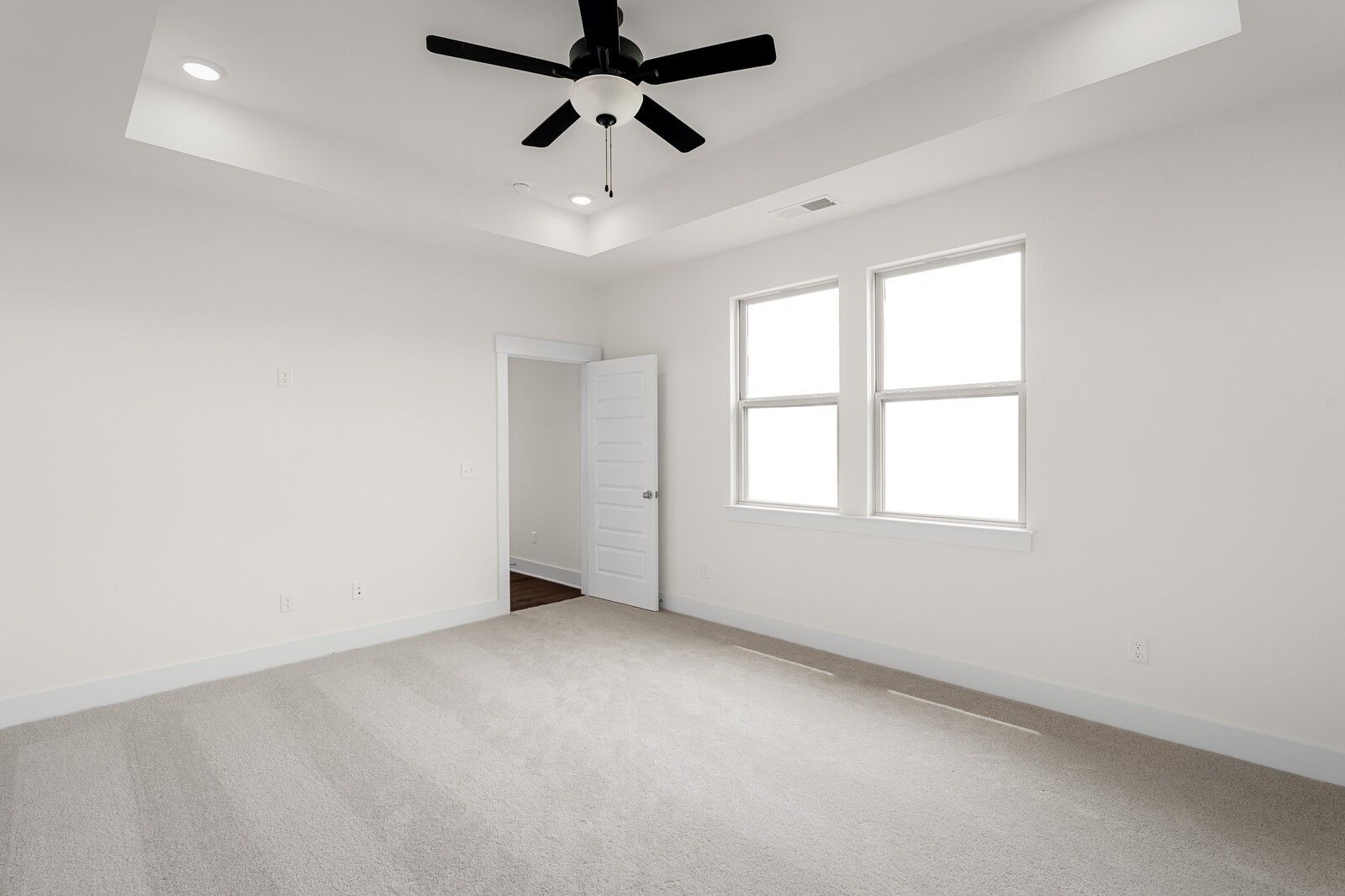 Bright bedroom with tray ceiling and ceiling fan in The Prairie C floor plan at Woods Crossing, Gallatin, Tennessee.