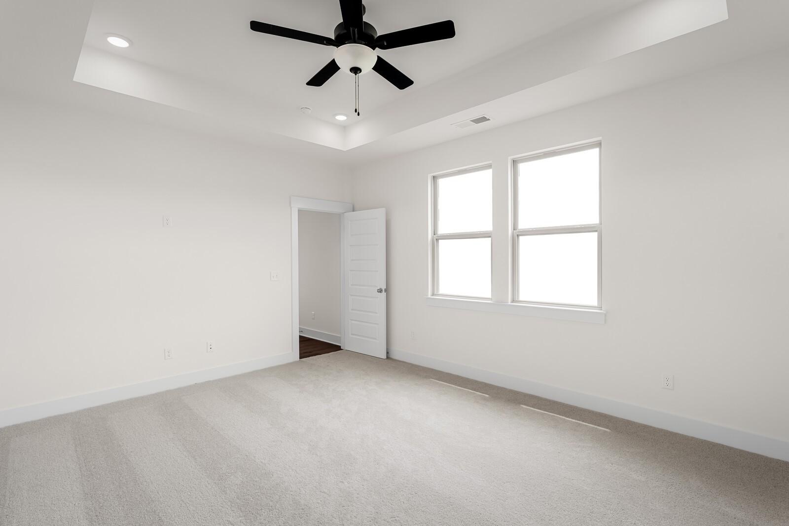 Bright bedroom with tray ceiling and ceiling fan in The Prairie C floor plan at Woods Crossing, Gallatin, Tennessee.