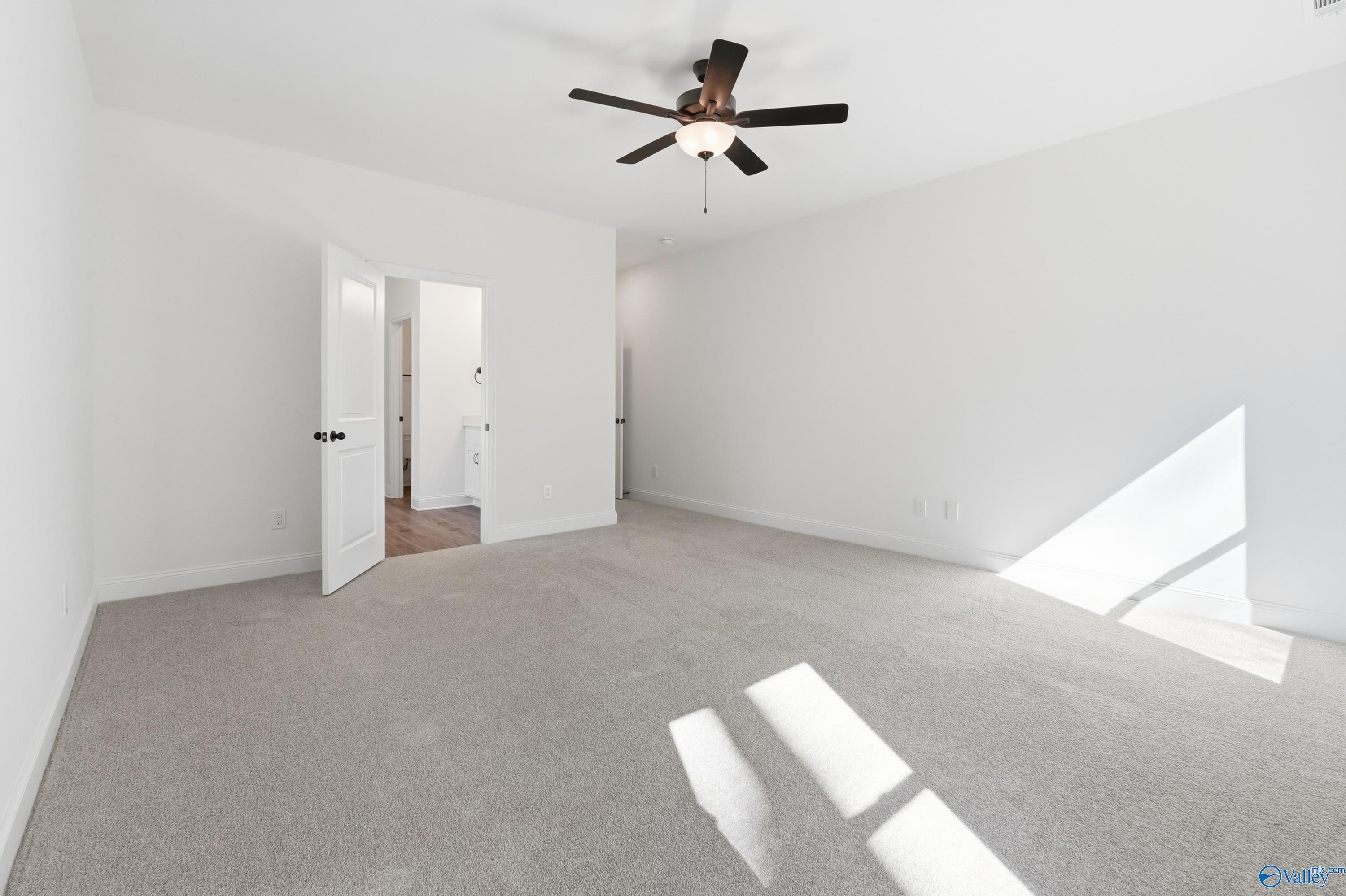 Spacious bedroom with ceiling fan, open doors to bath and closet in Davidson Homes The Rockford D, Hazel Green, Alabama