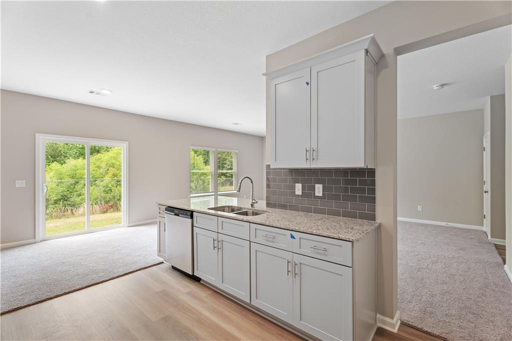 Modern kitchen with white cabinets, granite counters, subway tile backsplash, and sliding doors to lush backyard in Davidson Homes The Bartlett, Phenix City, AL