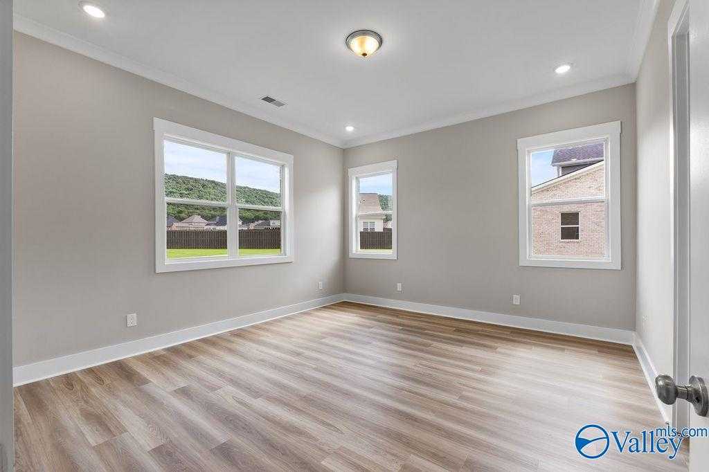 Bright bedroom with light gray walls, large windows overlooking hills, luxury vinyl plank flooring in Evermore Homes The Oxford, Owens Cross Roads, Alabama
