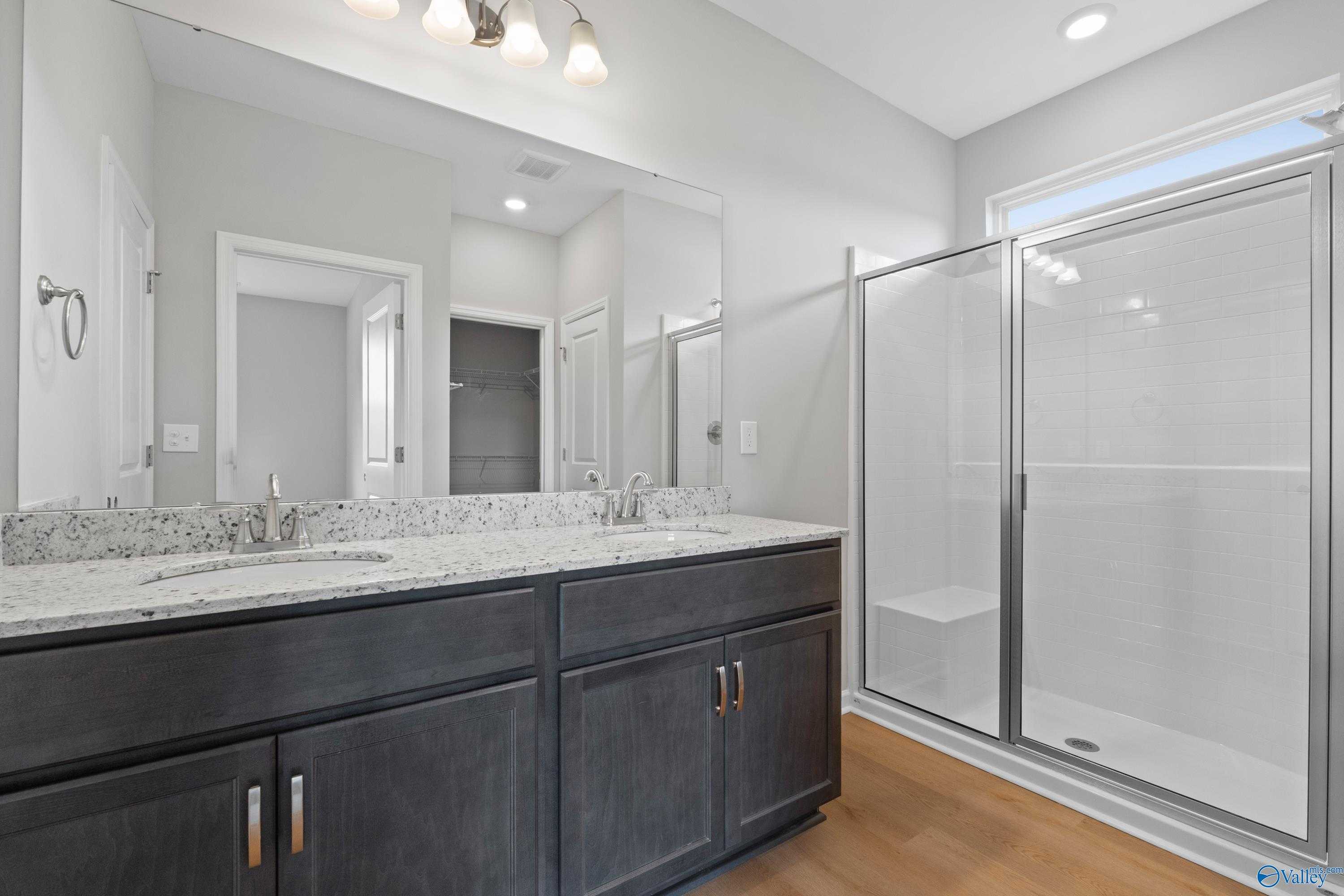 Modern master bathroom with double vanity, gray cabinets, quartz counters, frameless glass shower in Evermore Homes The Aurora, Harvest AL