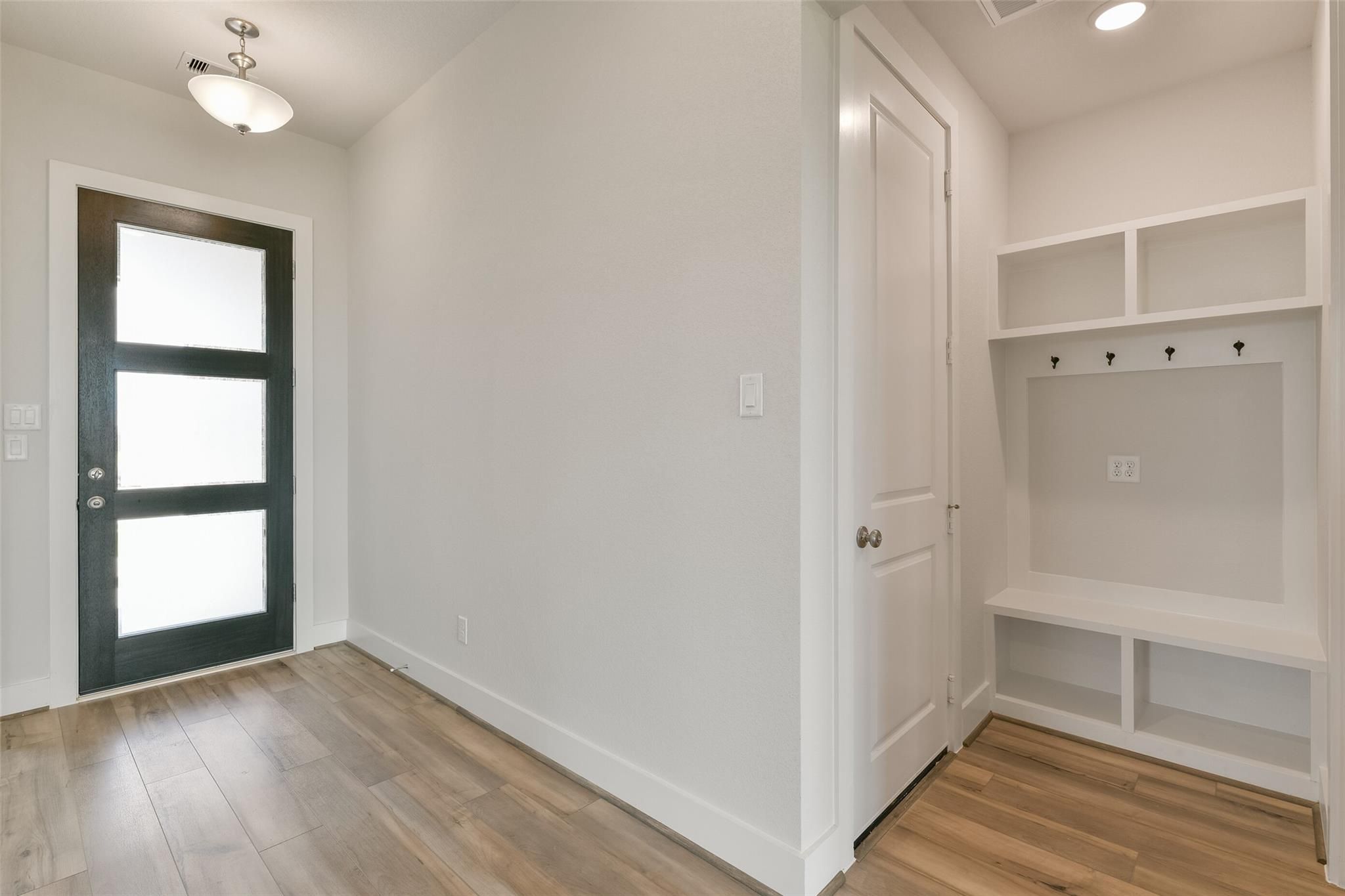 Modern entryway with frosted glass door, built-in bench, hooks and shelves in Davidson Homes The Edward A, Lago Mar, Texas City