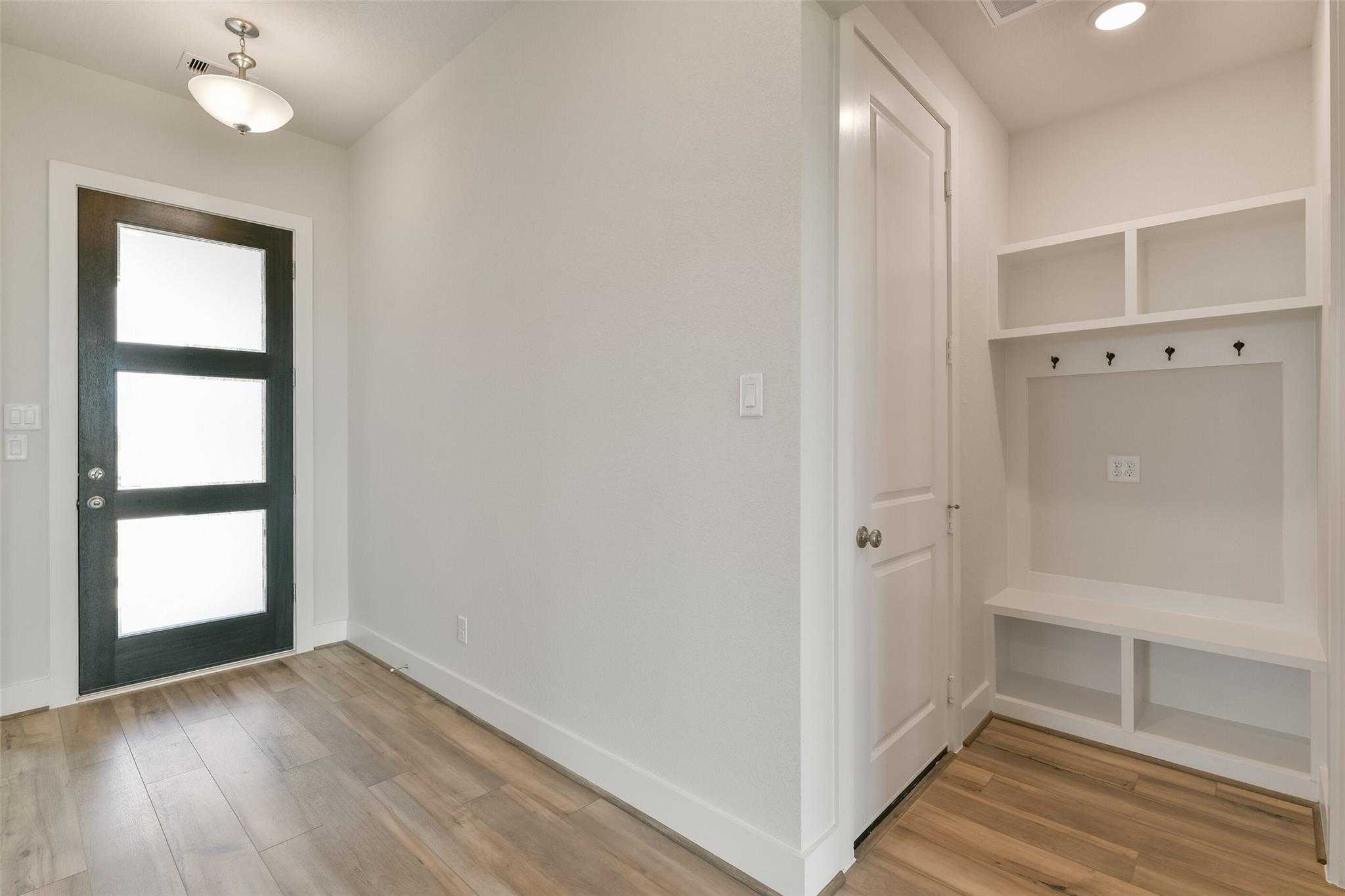 Modern entryway with frosted glass door, built-in bench, hooks and shelves in Davidson Homes The Edward A, Lago Mar, Texas City