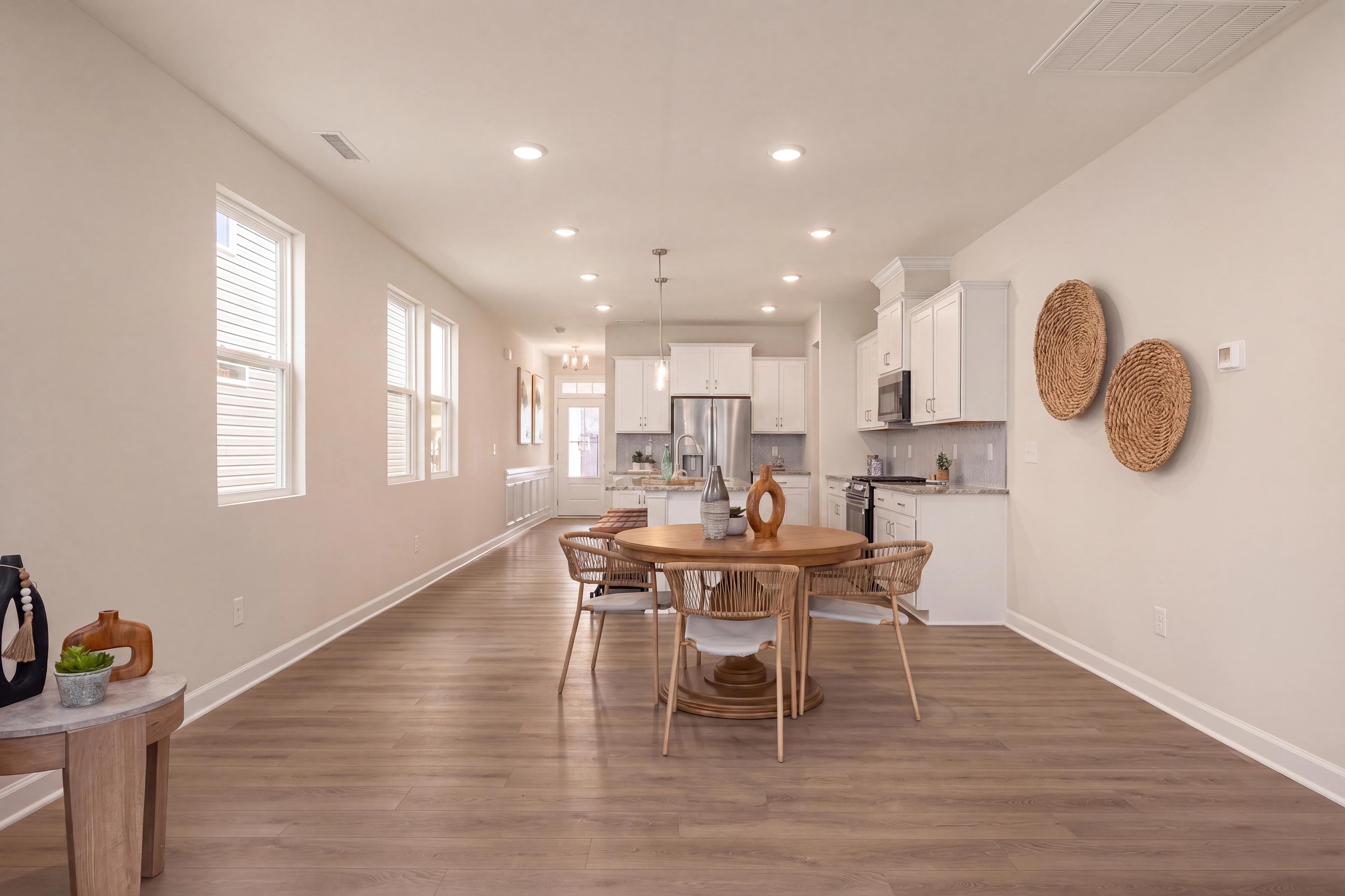 Open-concept kitchen and dining area at Gregory Village in Lillington, NC by Davidson Homes with modern white cabinetry.