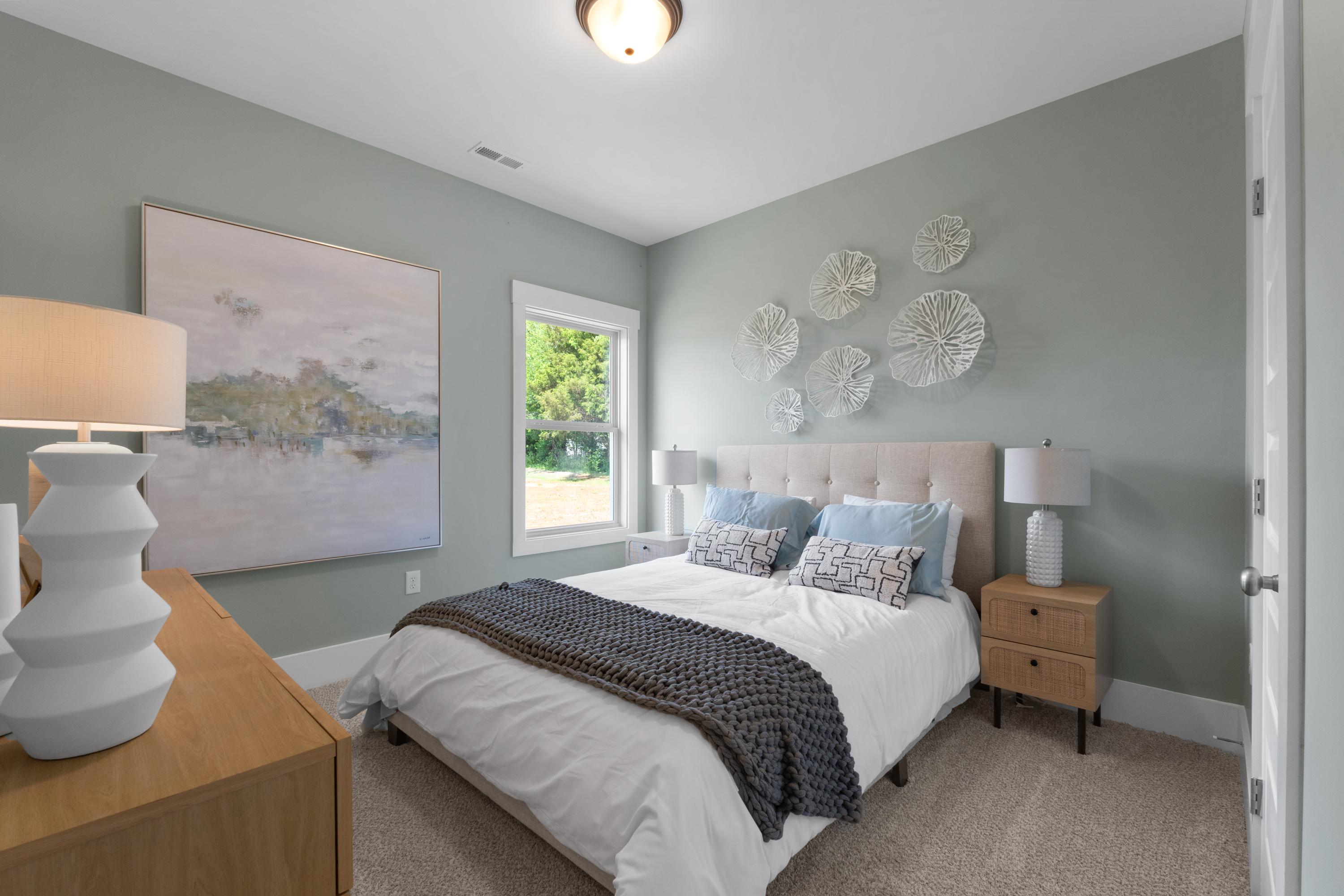 Serene bedroom at Hollon Meadow in Decatur AL with light blue walls, tufted bed, abstract art, and window view