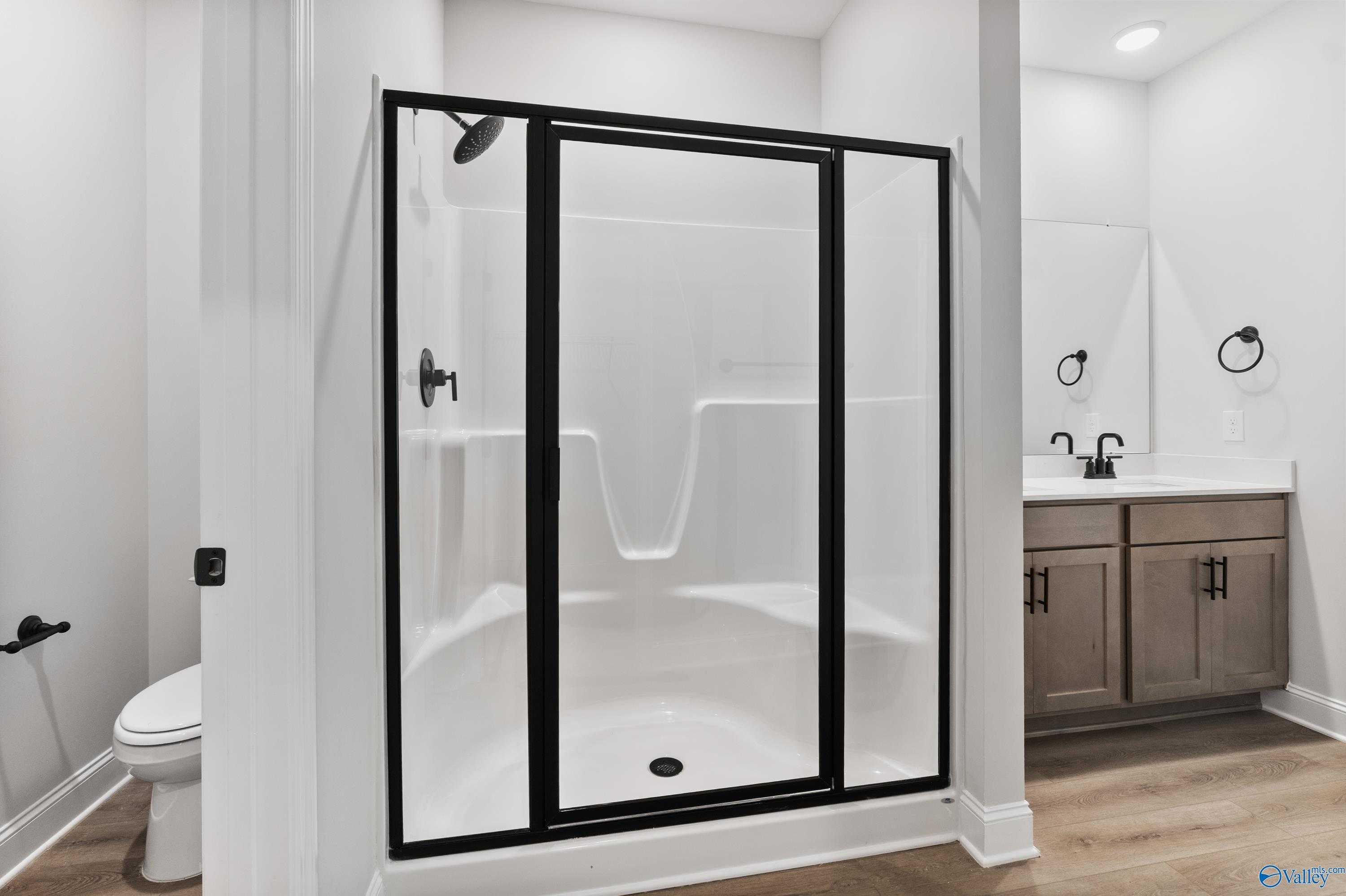 Modern master bathroom with frameless glass walk-in shower and double shaker vanity in Davidson Homes The Daphne, Huntsville AL