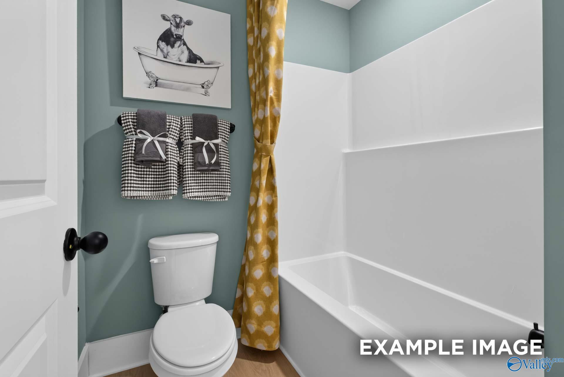 Stylish guest bathroom with tub-shower combo, gold patterned curtain, and teal walls in Davidson Homes Ashport K plan, Hazel Green