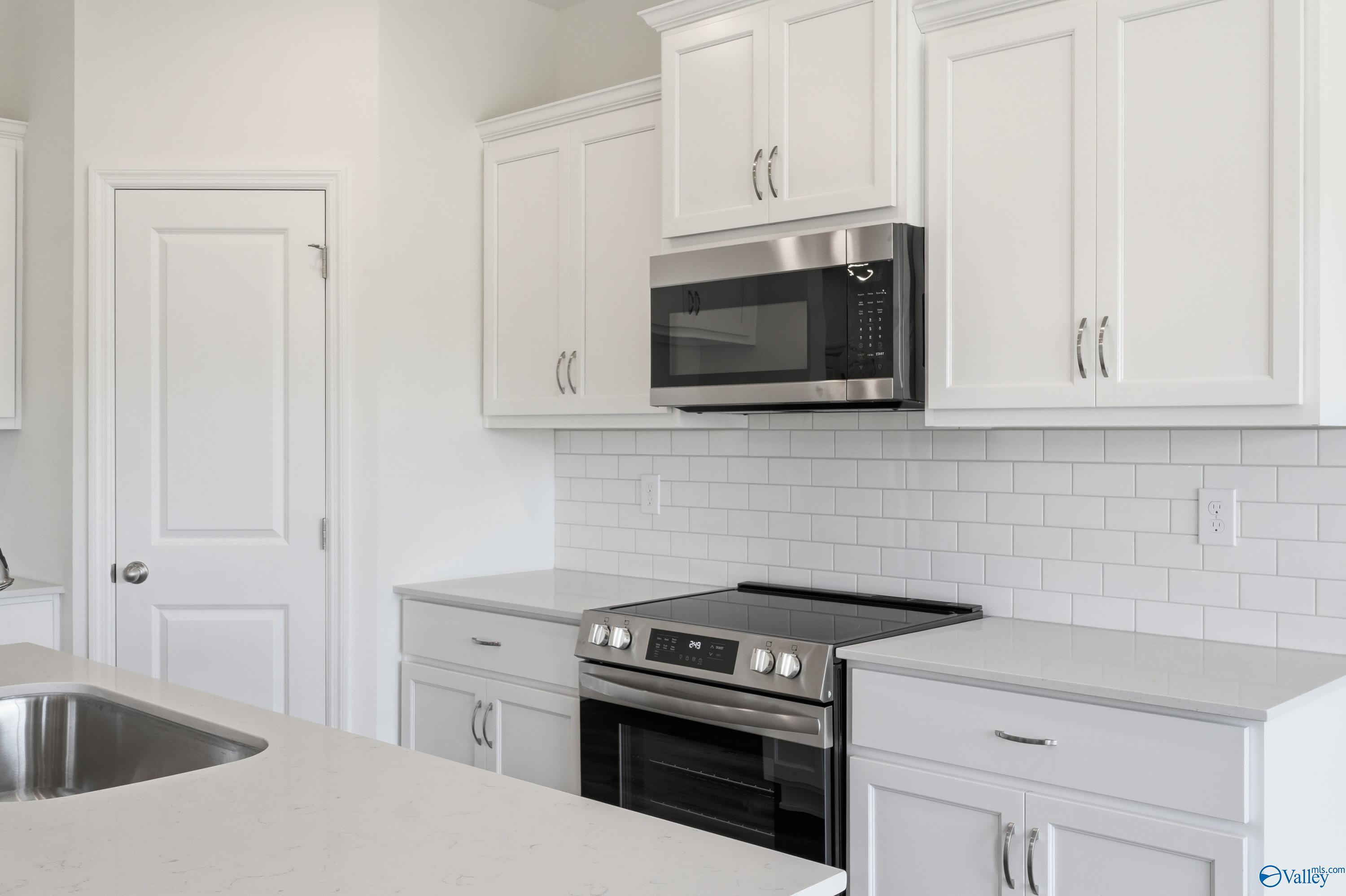 Modern kitchen with white cabinets, subway tile backsplash, and stainless appliances in The Asheville, Jaguar Hills home.