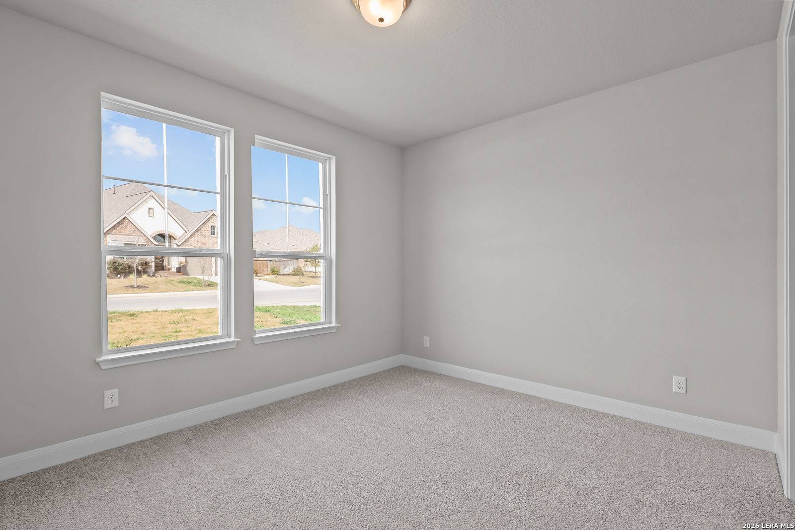 Bright empty bedroom with large sunny windows and gray carpet in Davidson Homes The Rockford G, Ladera, San Antonio