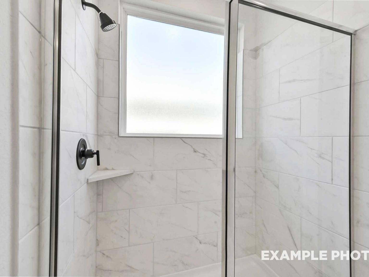 Modern walk-in shower with marble-look tile and glass enclosure in The Sequoia C floor plan, Sundance Cove, Crosby, Texas.