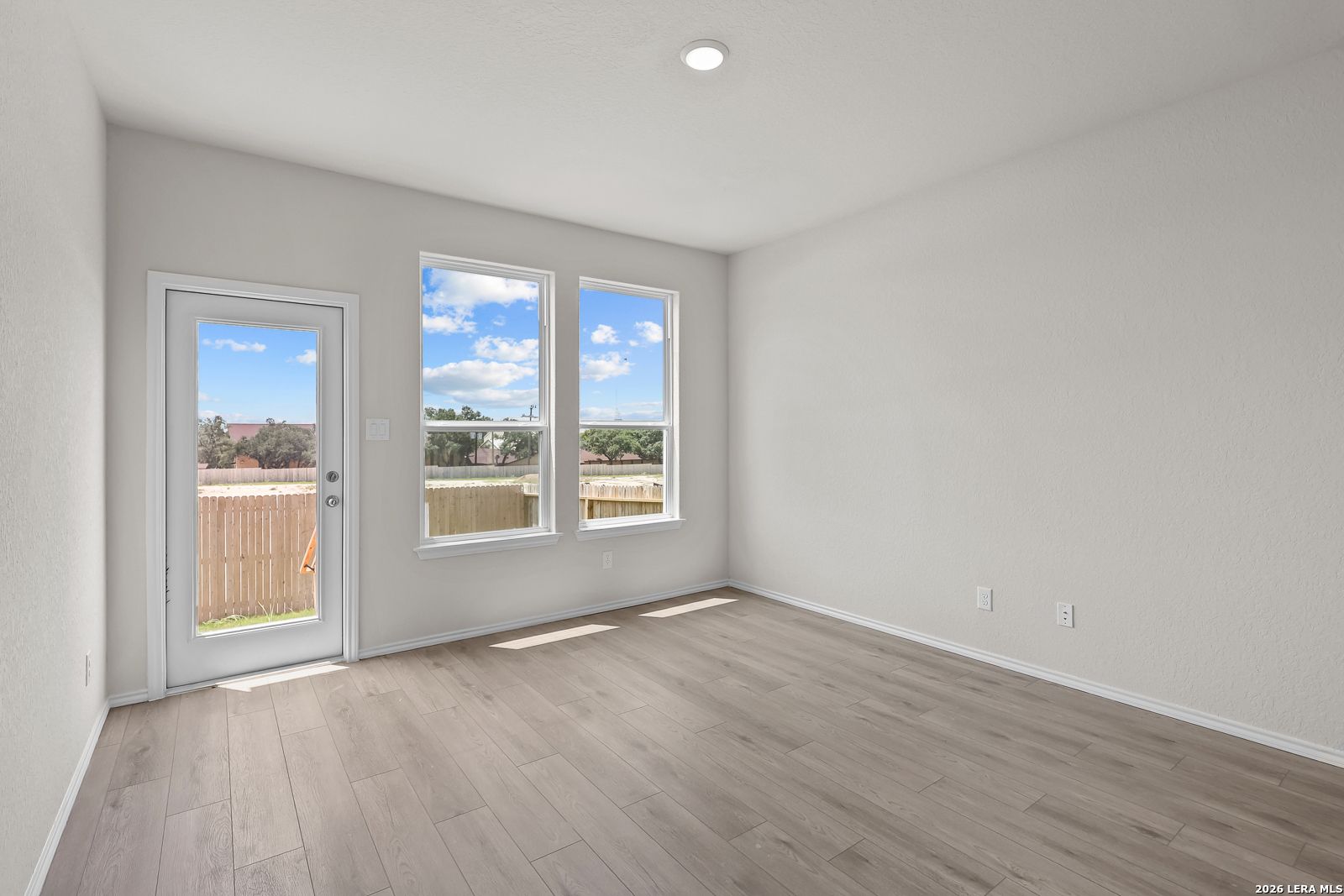 Bright living area with wood-look flooring and backyard access in The Gillian B floor plan, Meadows at Oak Creek, SA.