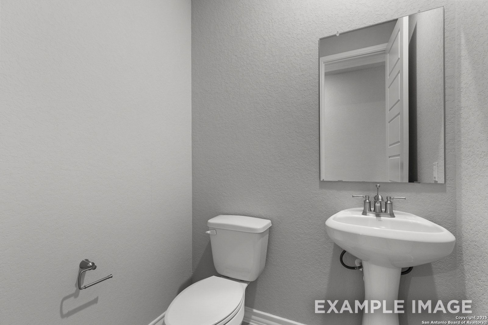 Modern powder room in The Oxford home design featuring a pedestal sink, white toilet, and wall-mounted mirror.