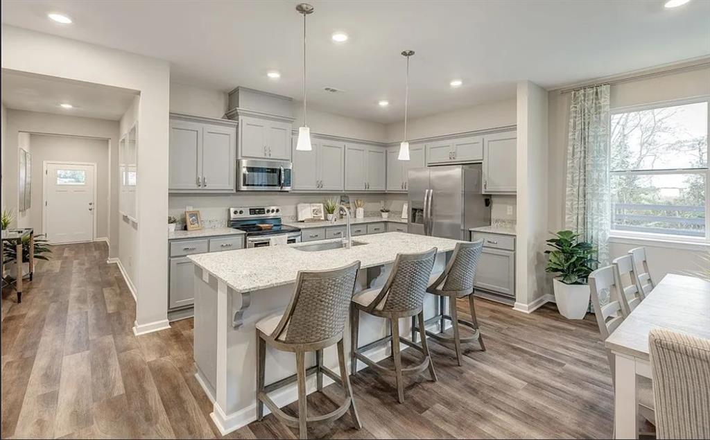 Gray shaker kitchen with granite island, stainless appliances, and pendant lighting in Davidson Homes Aurora D, Opelika, Alabama