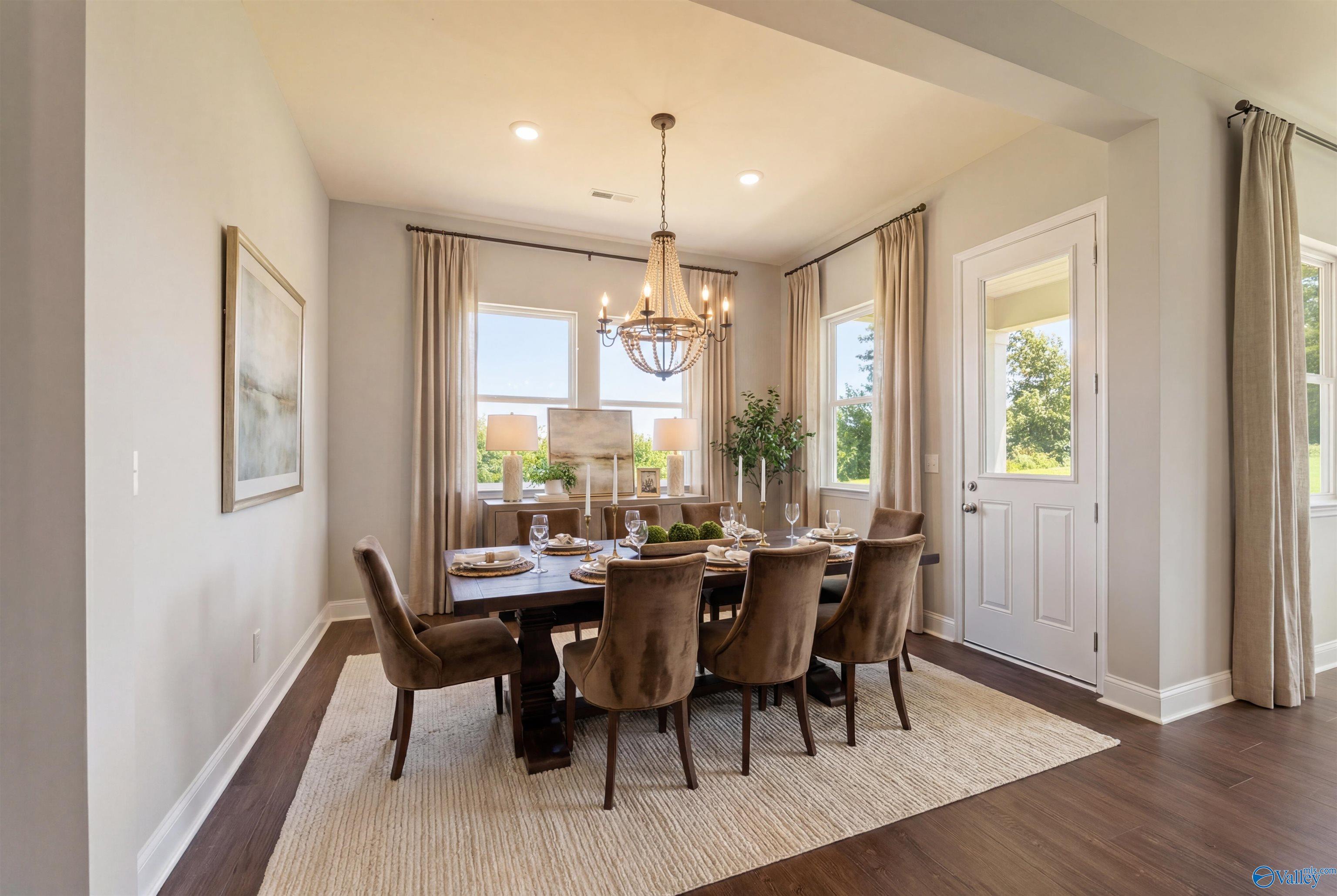 Elegant formal dining room with chandelier, wooden table, and large windows in Davidson Homes The Arcadia B, Huntsville, Alabama