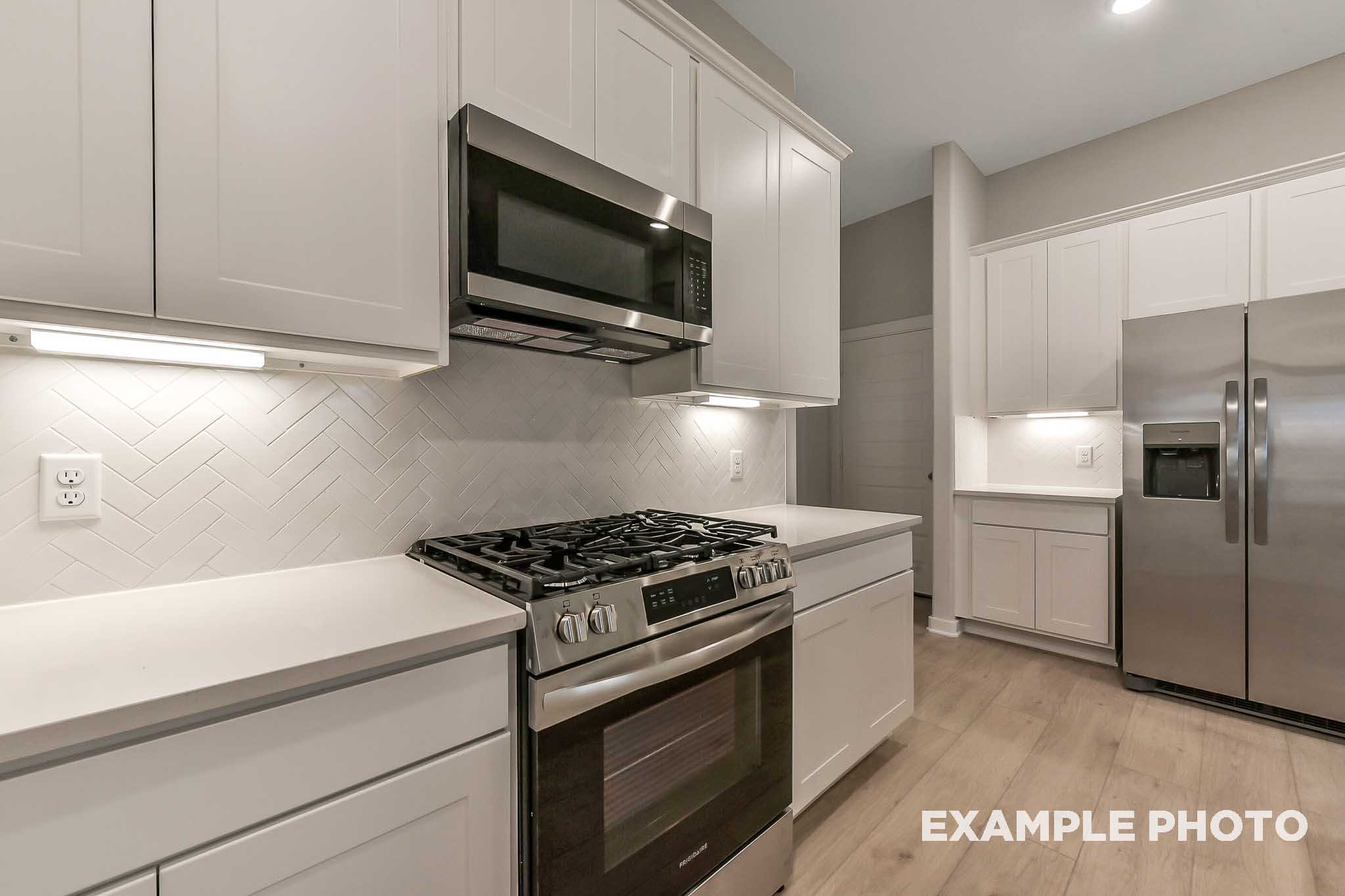 Modern kitchen in The Laguna B by Davidson Homes featuring white shaker cabinets, stainless steel appliances, and subway tile backsplash