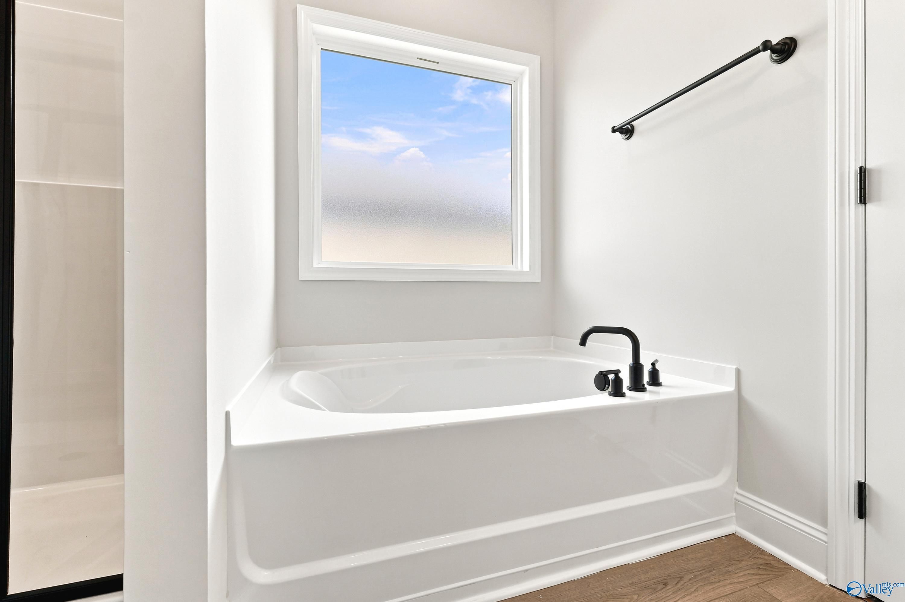 Modern soaking tub with matte black fixtures and privacy window in The Daphne floor plan by Davidson Homes, Meridianville.