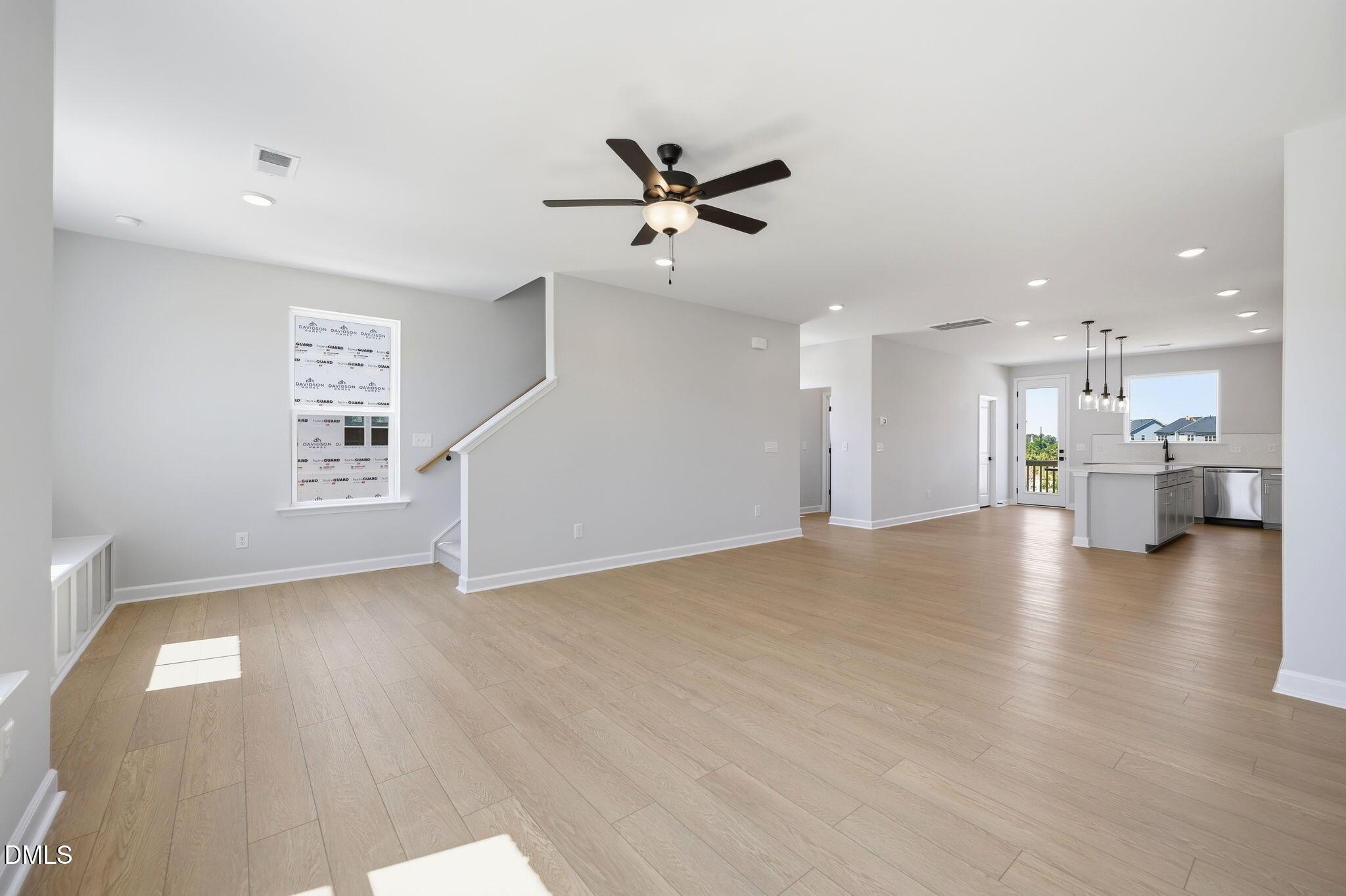 Open-concept living room with light wood floors and kitchen in The Avery floor plan at Forestville Yard Townhomes.