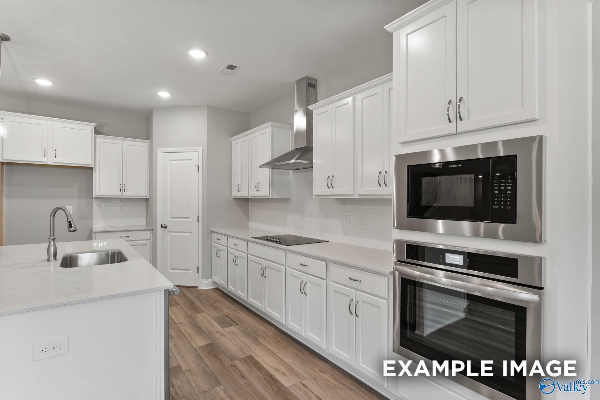 Bright modern kitchen with white shaker cabinets, stainless steel appliances, quartz island in Davidson Homes The Rockford, Madison, Alabama