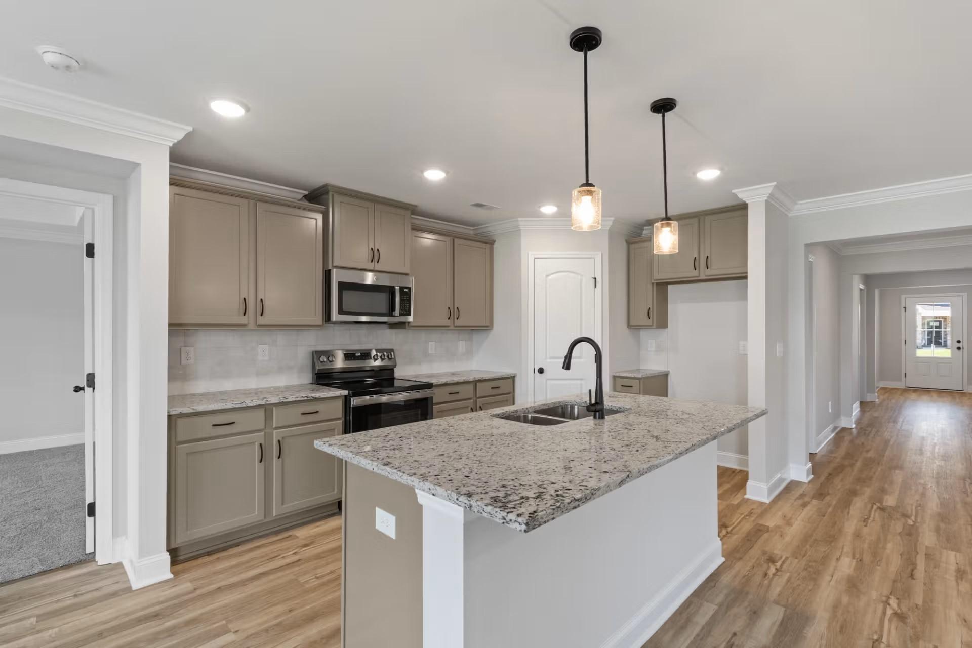 Modern open-concept kitchen with greige cabinets, granite countertops, stainless appliances, and island in The Everett D, Josephine, Texas