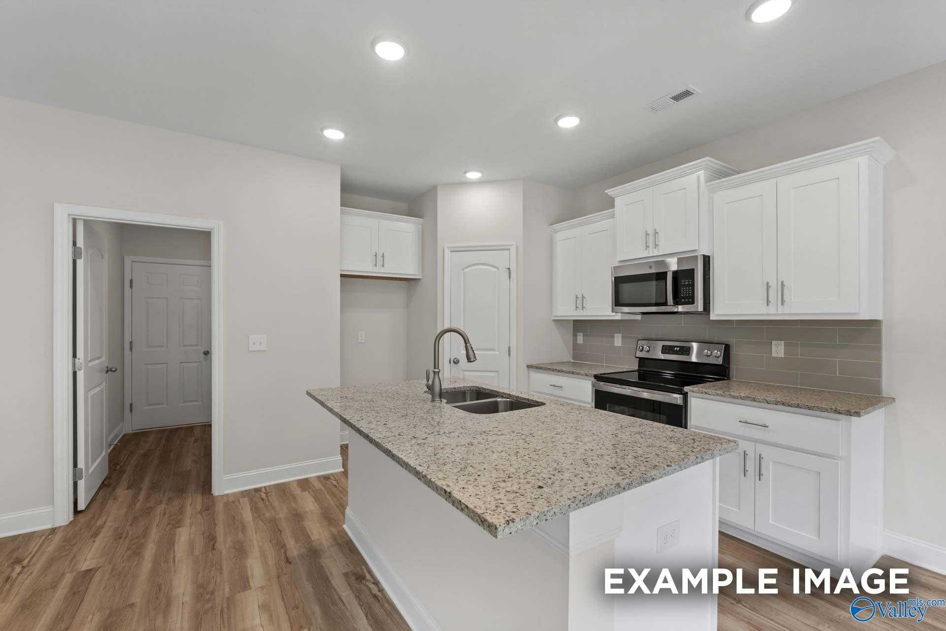Modern kitchen featuring white shaker cabinets, granite island sink, and stainless appliances in Davidson Homes The Butler plan, Toney, AL