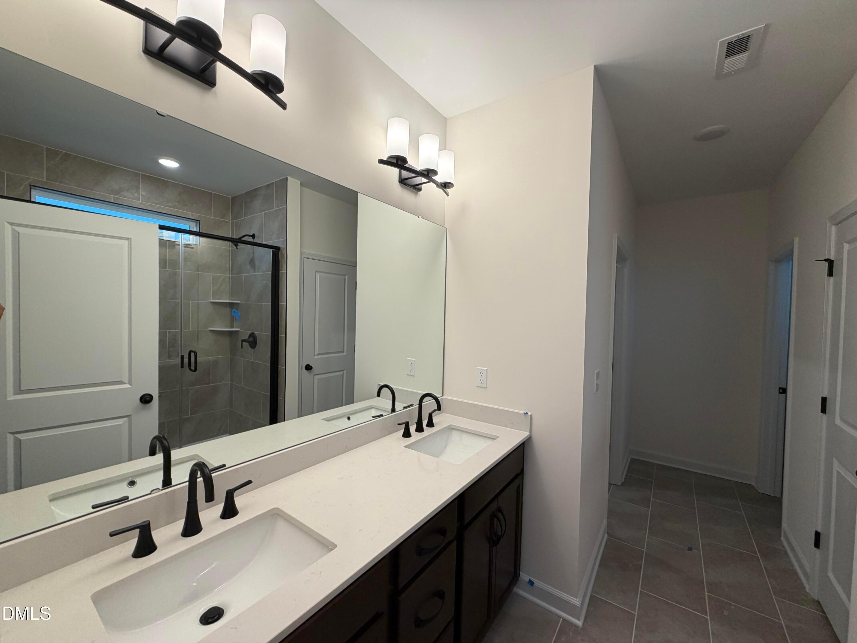 Double vanity bathroom with white quartz counters, matte black fixtures, and tiled walk-in shower in Davidson Homes The Ashport M plan