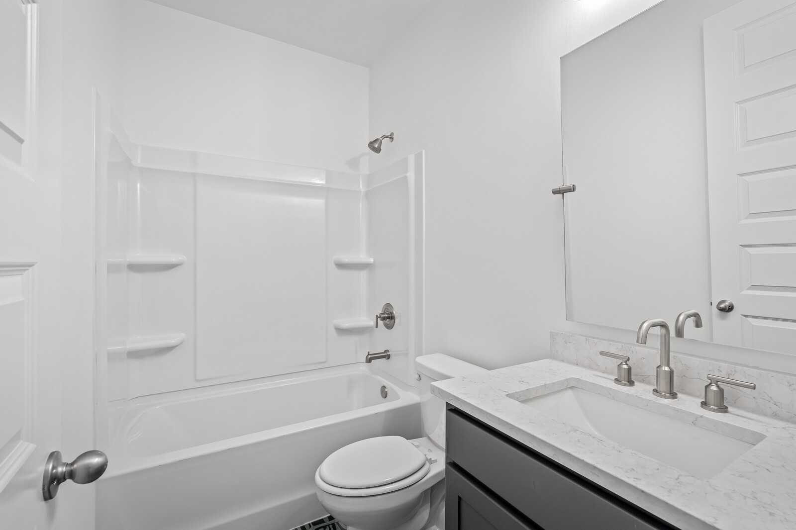 Modern guest bathroom featuring tub-shower combo, quartz vanity sink, white toilet in Davidson Homes The Hawkins, Murfreesboro, TN