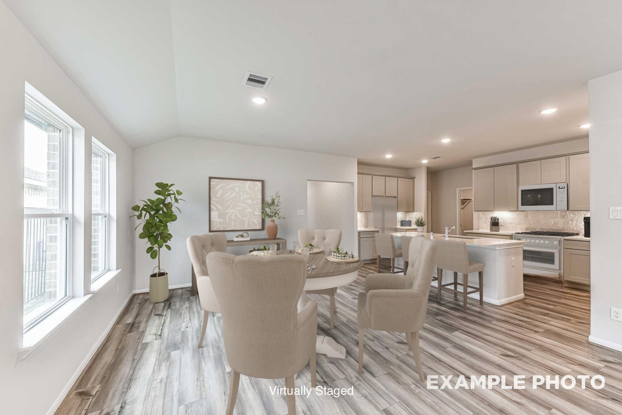 Open-concept dining area and kitchen with wood-look flooring in The Laguna C floor plan by Davidson Homes in Katy, Texas.