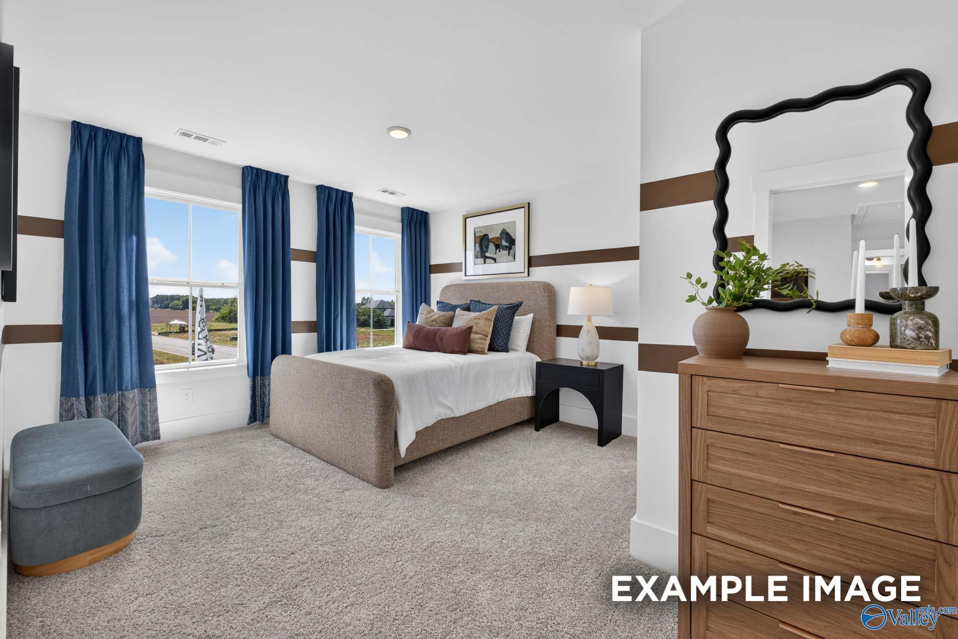 Bright model bedroom with upholstered bed, blue curtains, and wood dresser in Davidson Homes The Ashport K, Hazel Green, Alabama